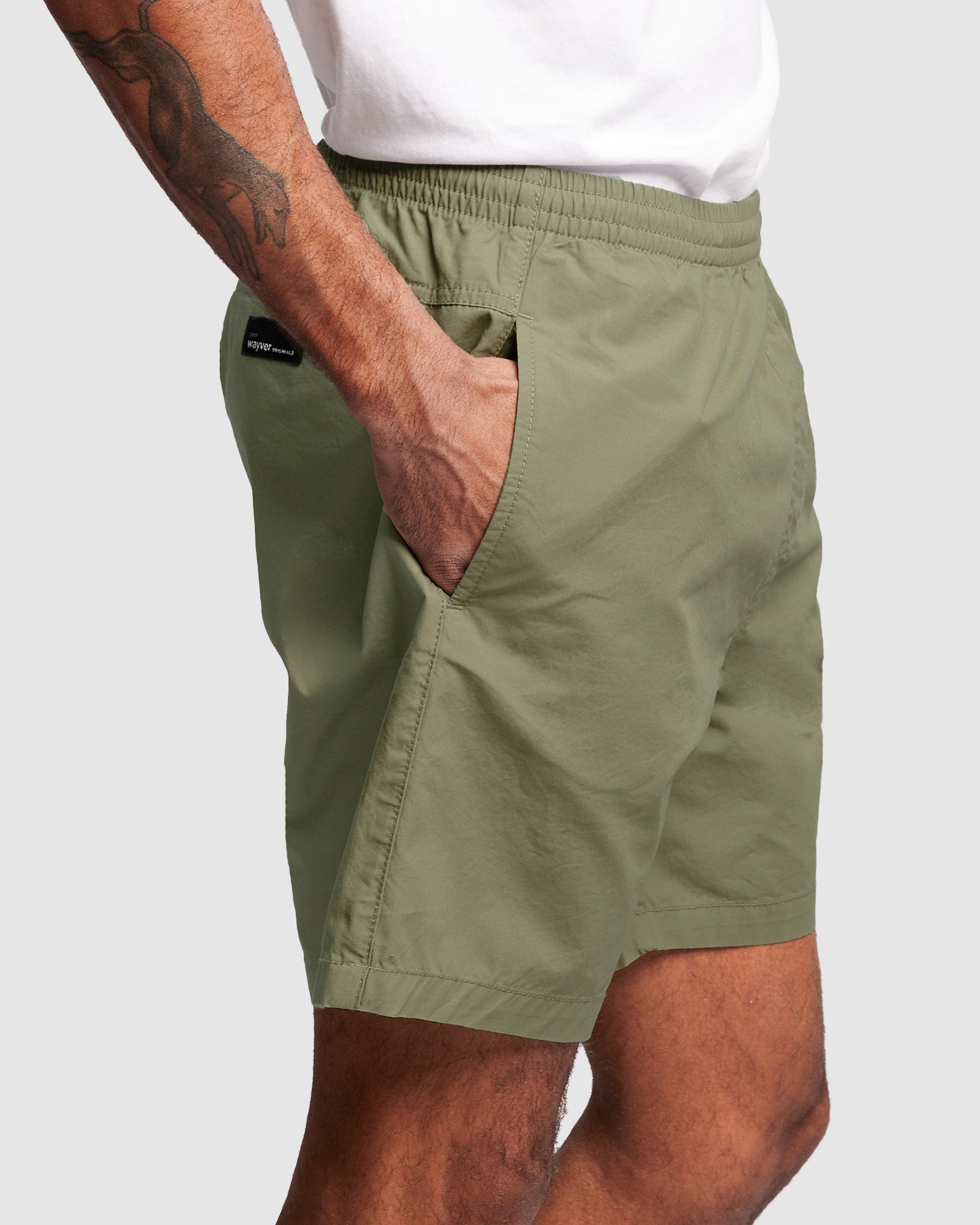Person wearing olive green shorts, with elasticated waist on a white background, side view close up shot