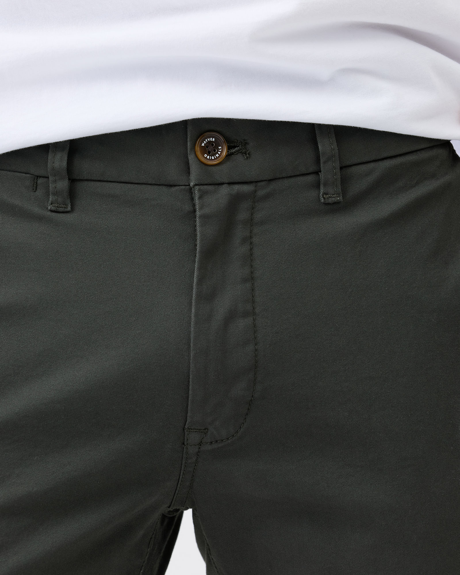 Close-up of dark green pants with a white shirt underneath