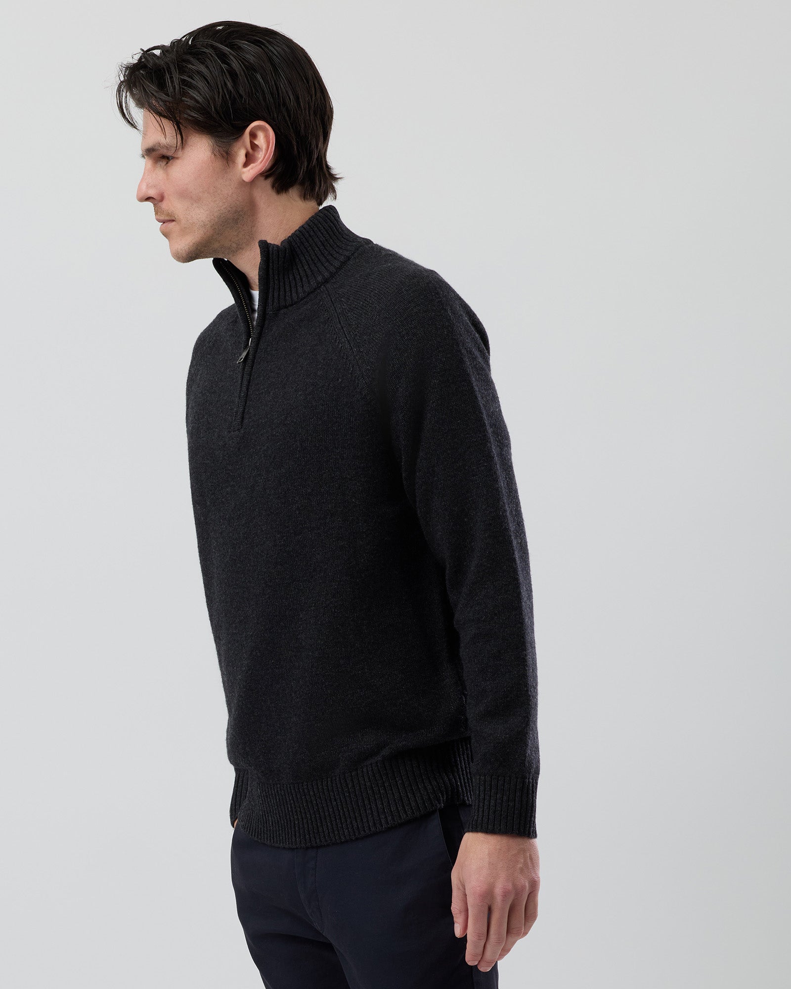Angled side view of a men's charcoal wool blend quarter zip knit showing the modern silhouette and premium jersey knit construction.