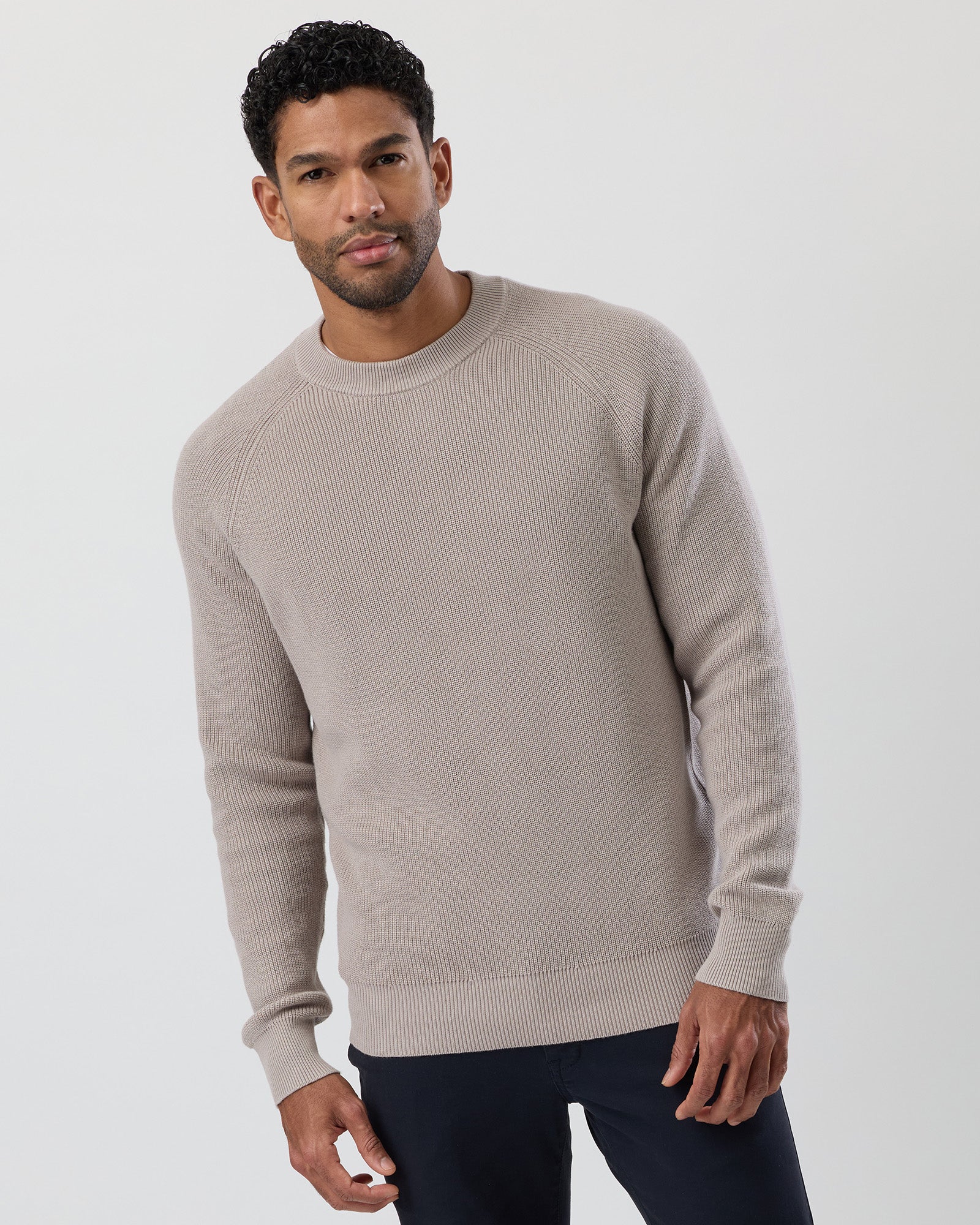 Man wearing a beige sweater against a plain background
