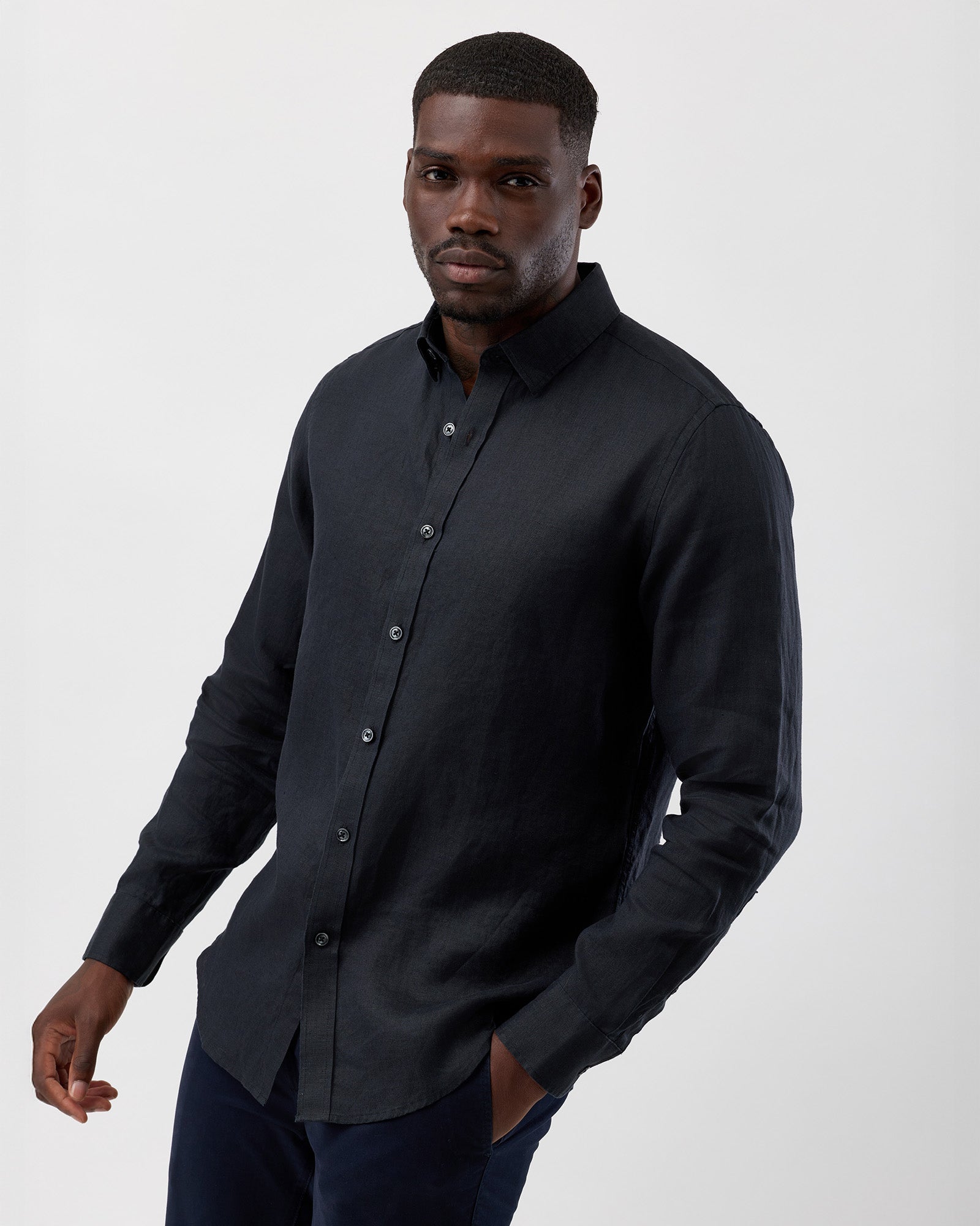 Man wearing a wayver black linen long sleeve summer shirt against a white background, side profile