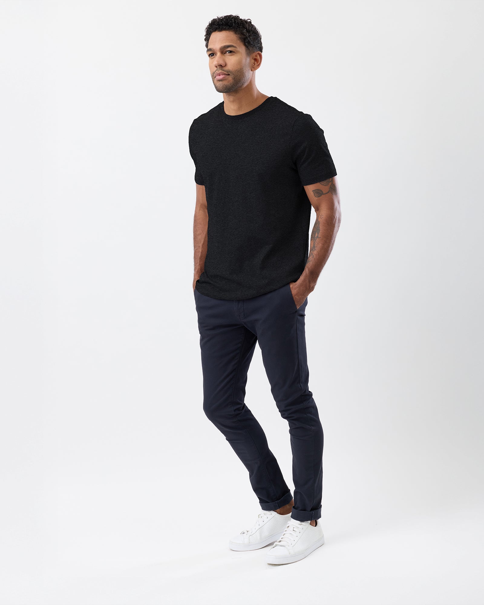 Man wearing a black Wayver t-shirt, dark jeans, and white sneakers on a white background