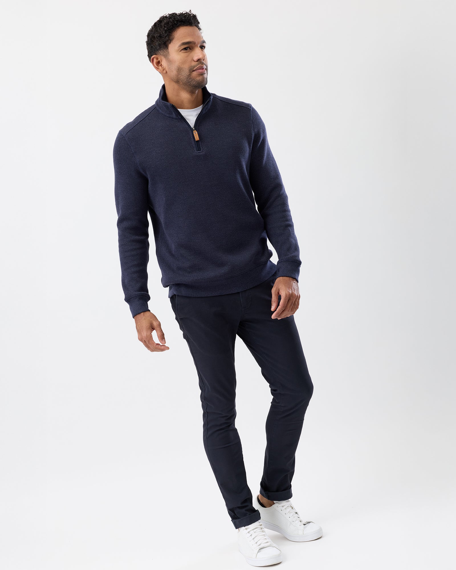 Essential men’s cotton knit layered over white t-shirt, worn with chinos and white sneakers, full body image