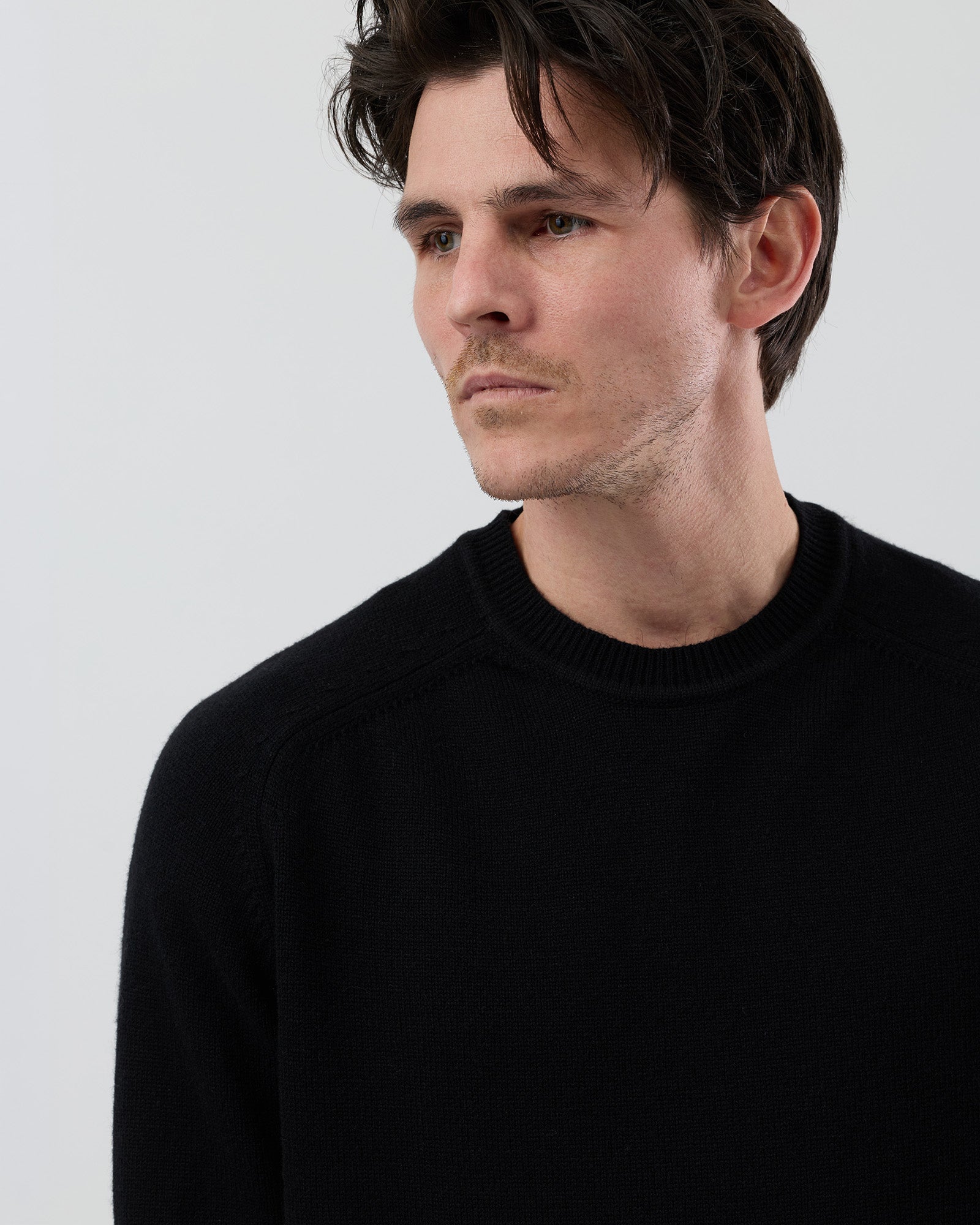 Close-up front view of a men's black wool blend crew neck sweater highlighting the premium knit texture and crew neckline.