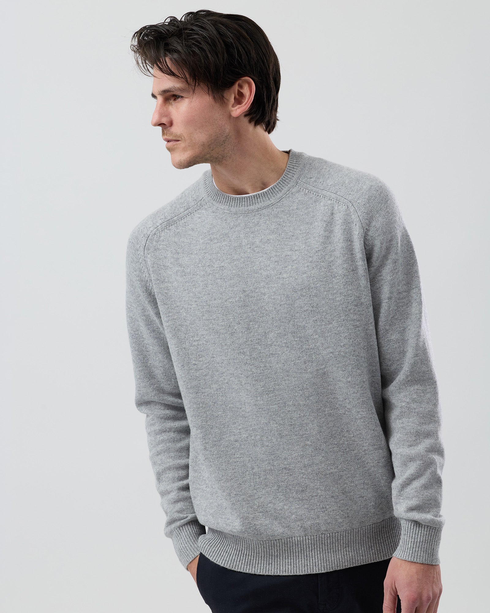 Male model wearing the Wayver Originals light grey wool blend crew neck knit jumper on a grey background, front cropped view highlighting the fit through the chest and sleeves.