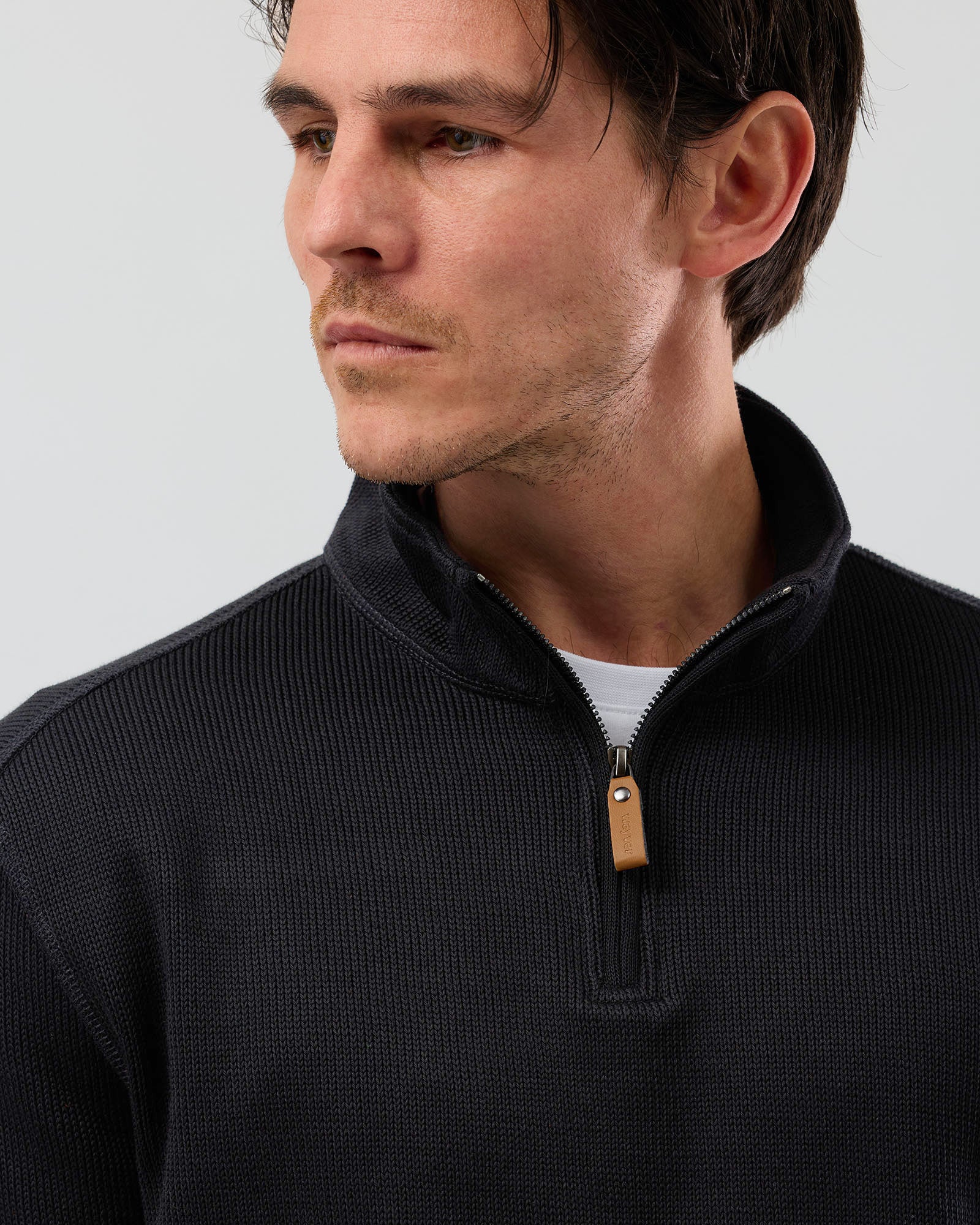 Detailed close-up of men's black French rib half zip sweatshirt, highlighting the textured 380gsm cotton-rich fabric, stand collar and leather zip pull.