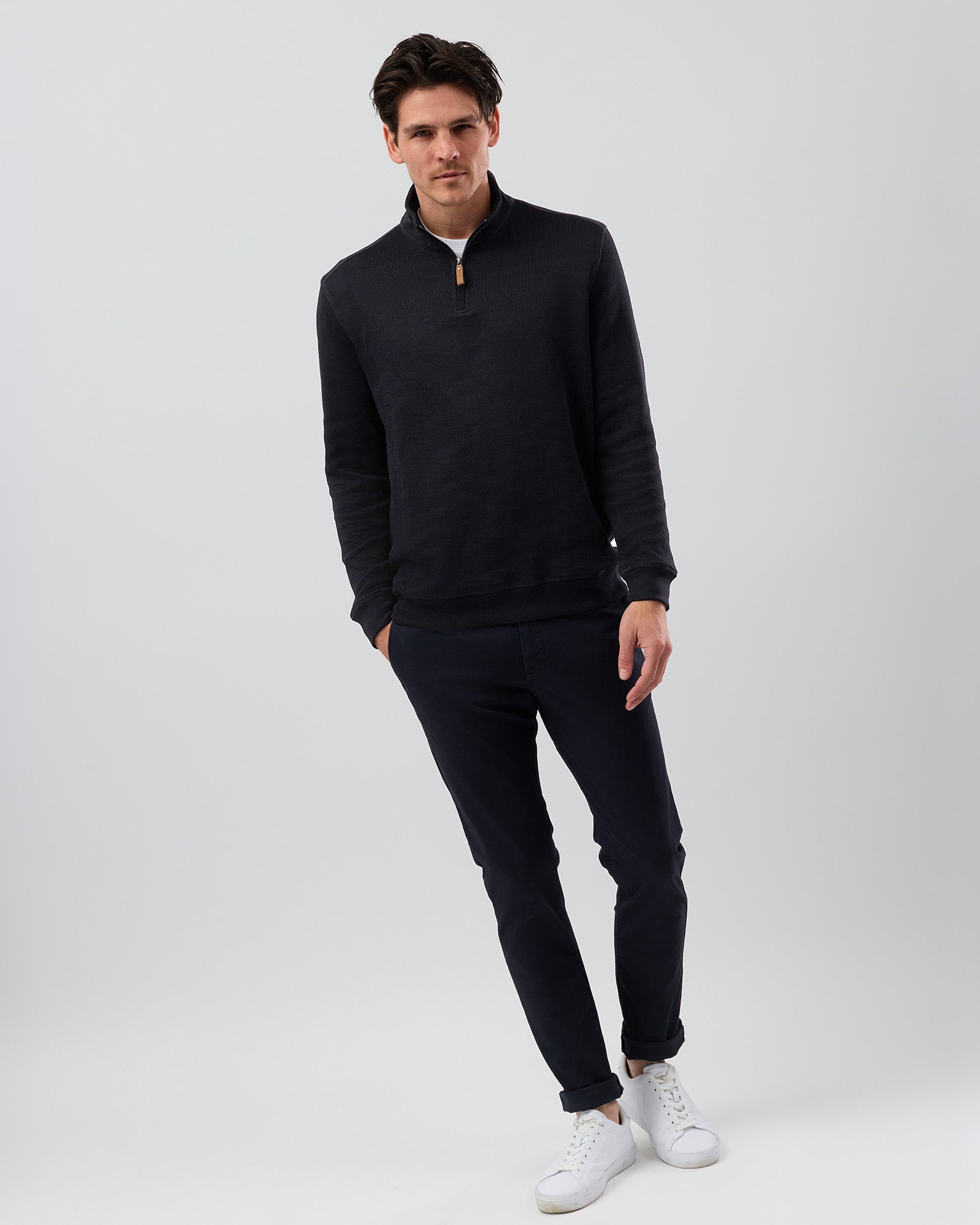 Men's black half zip jumper styled with navy chinos and white sneakers, showcasing the fit of this cotton-rich quarter zip sweater for smart casual wear.
