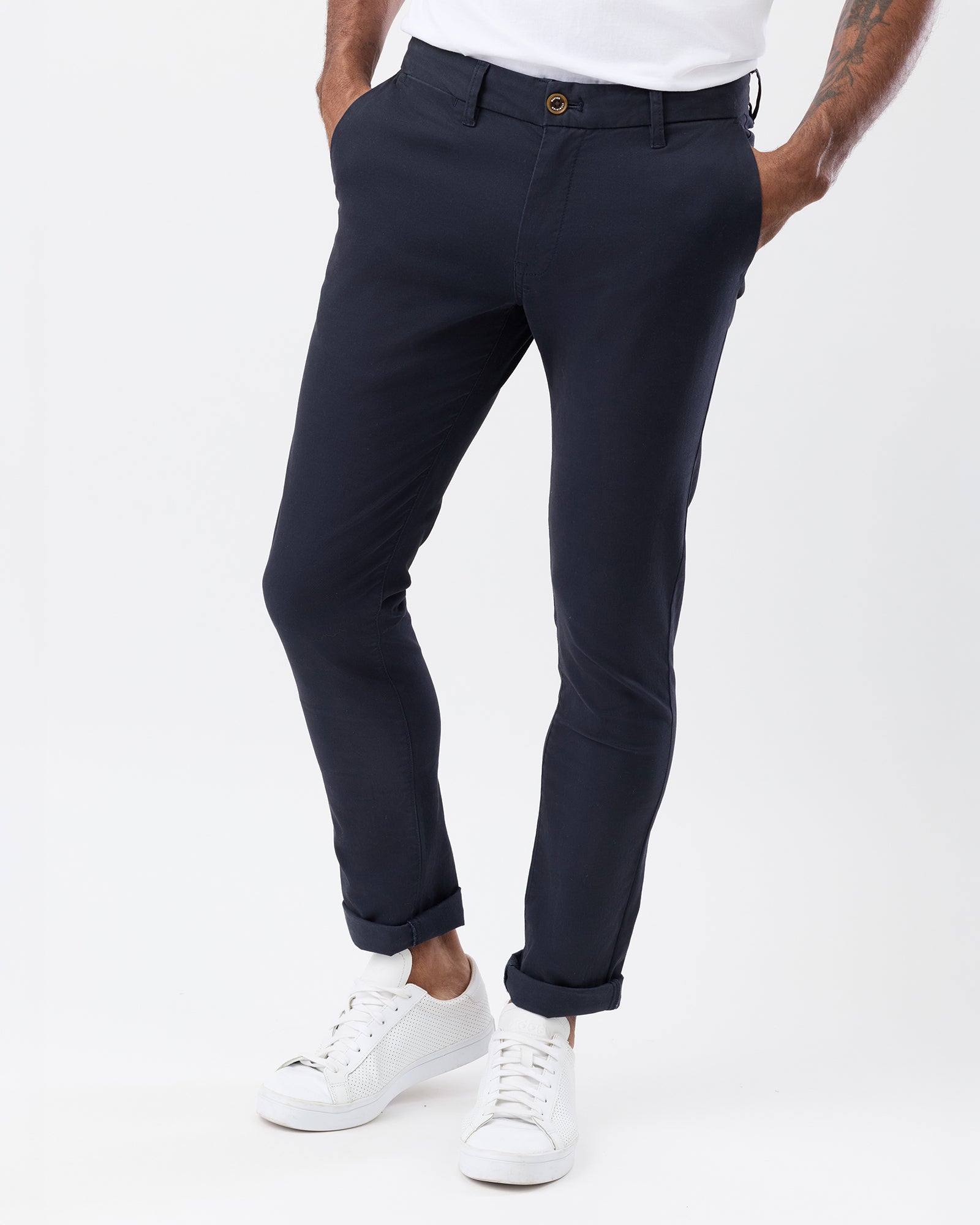 Front view of men's navy slim stretch chinos showing the waistband, tapered leg fit and rolled hems, paired with white sneakers.