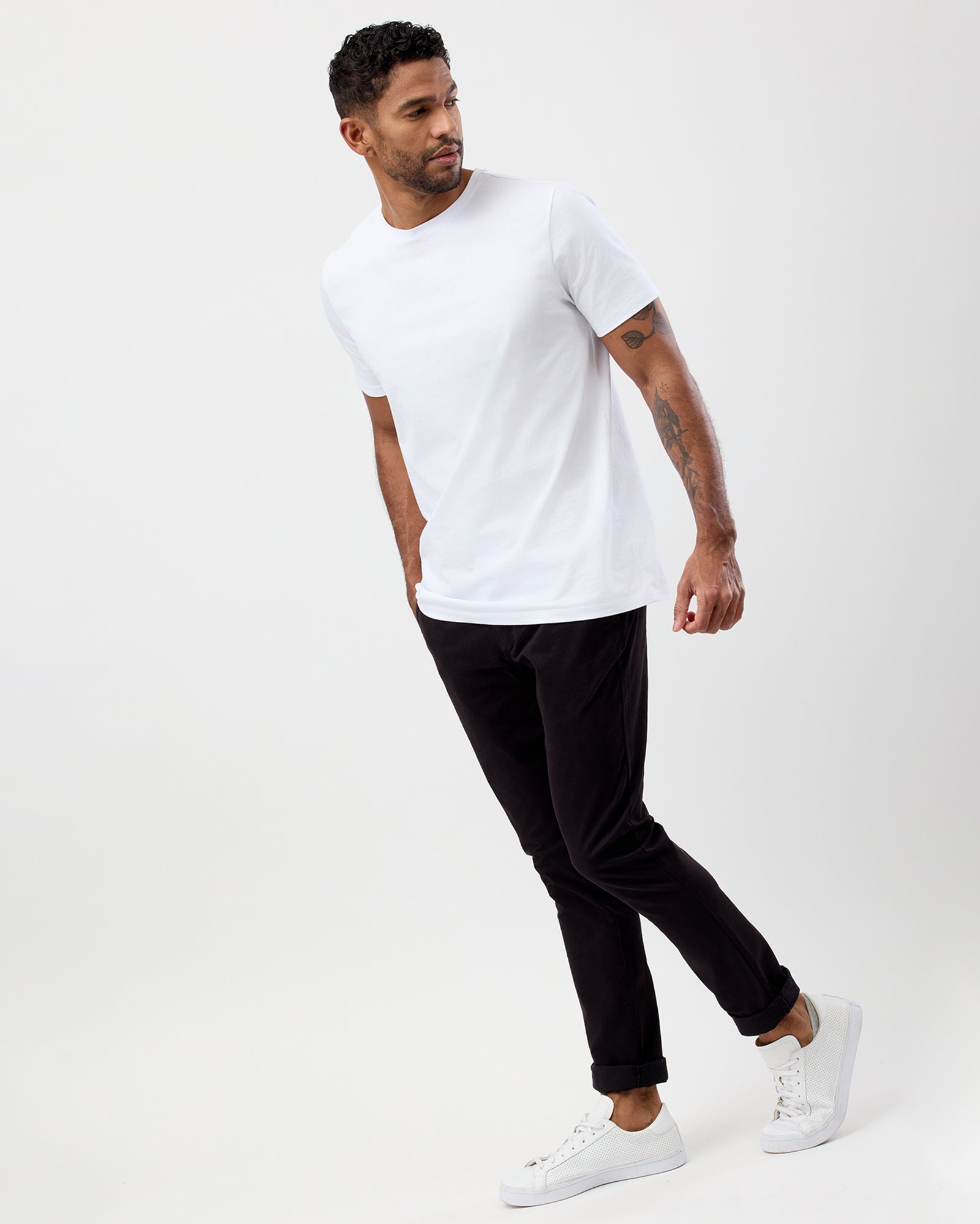 Wayver Originals men's black slim stretch chino pantsstyled with a white t-shirt and sneakers, shown in a casual standing pose.