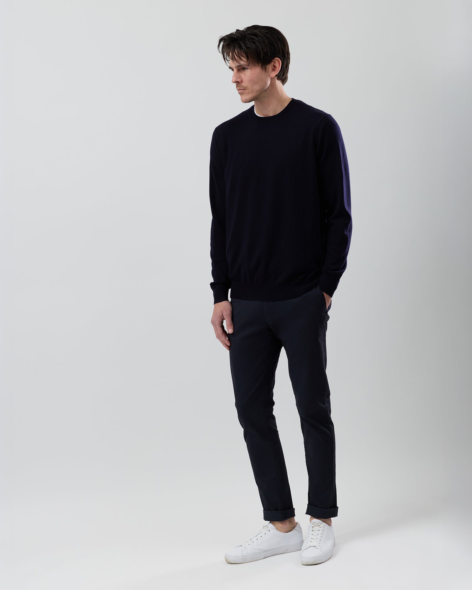 Full-length side profile of a men's navy Australian ultrafine merino wool knit paired with navy chinos on a grey background.