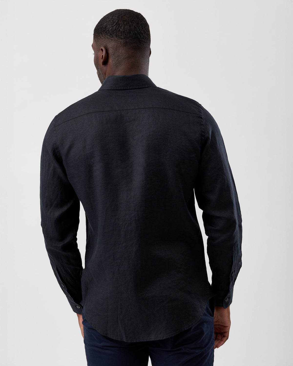Man wearing a black summer linen shirt from behind on a white background