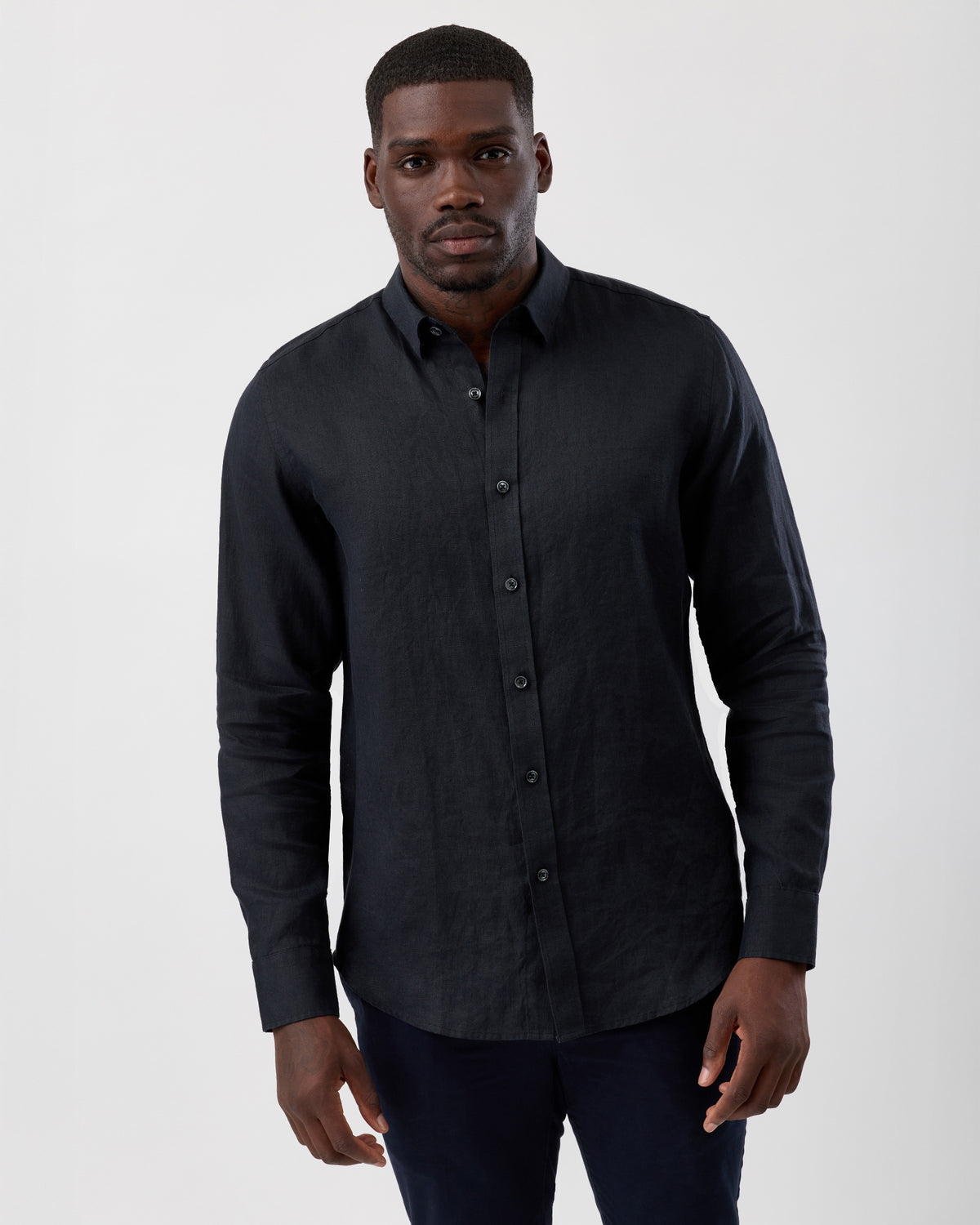 Man wearing a black linen button-up shirt against a white background, front cropped image