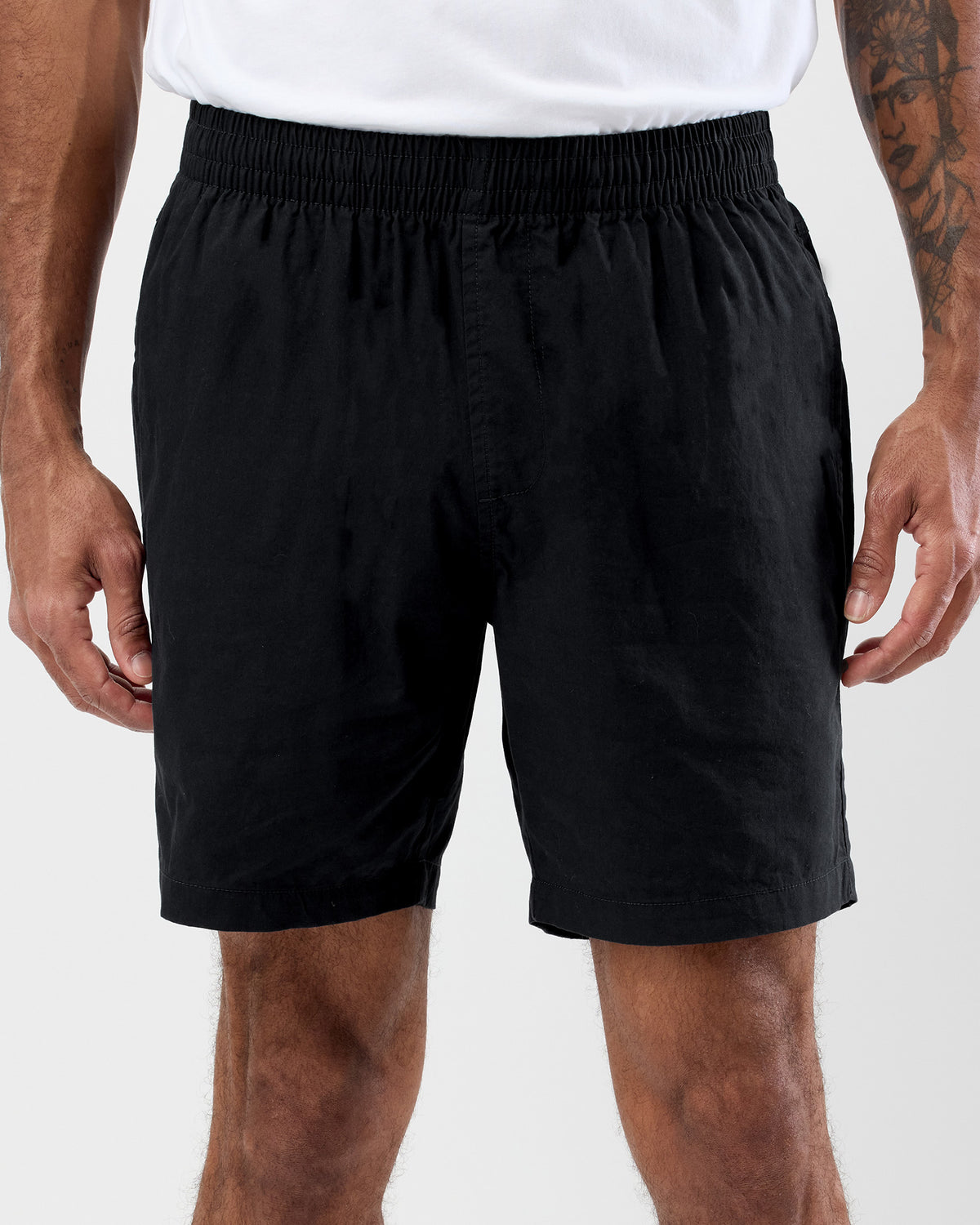 Person wearing black shorts on a white background, close up shot