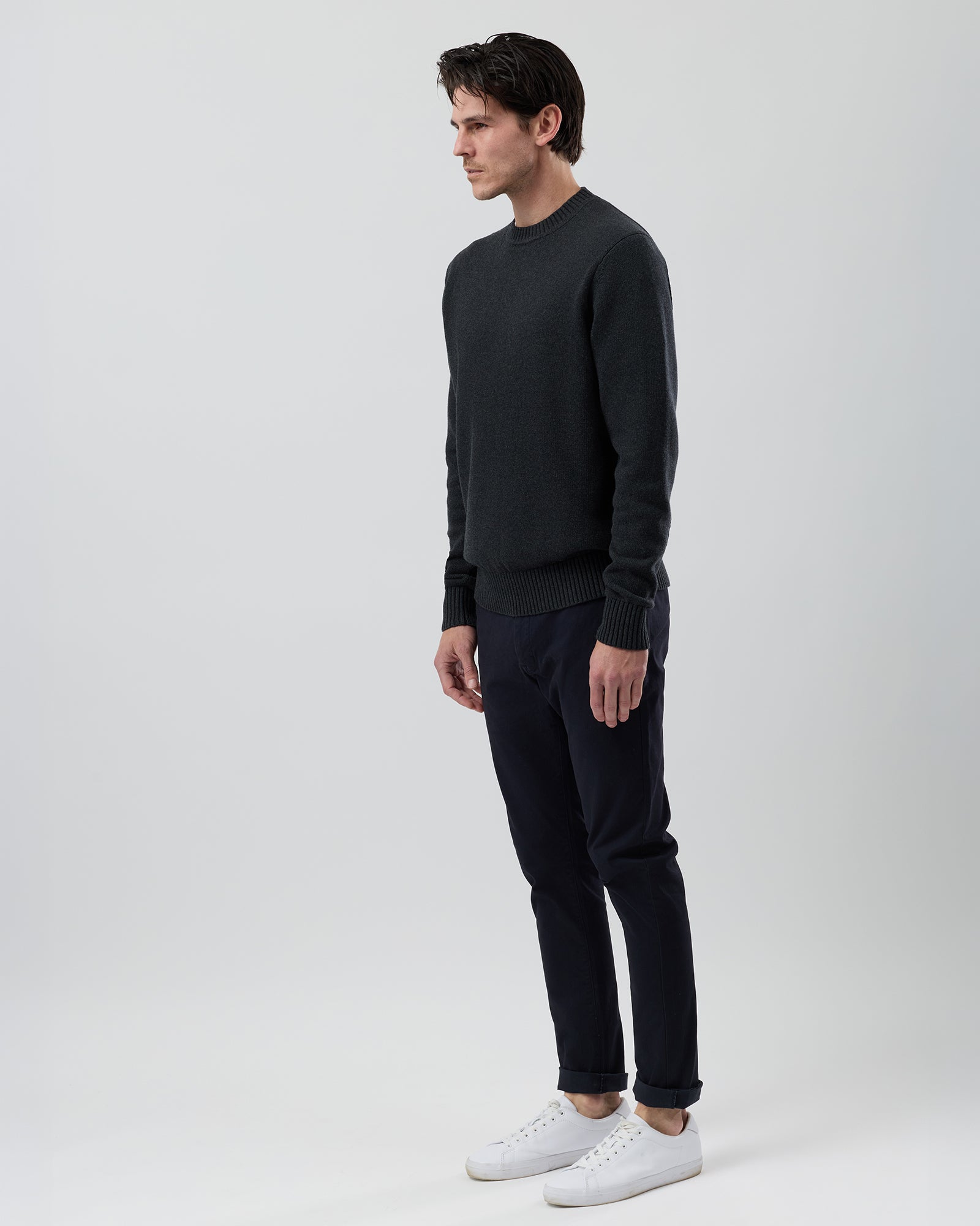 Side profile of a male model wearing the Wayver charcoal cotton crew neck jumper showing the modern regular fit and slim sleeves.
