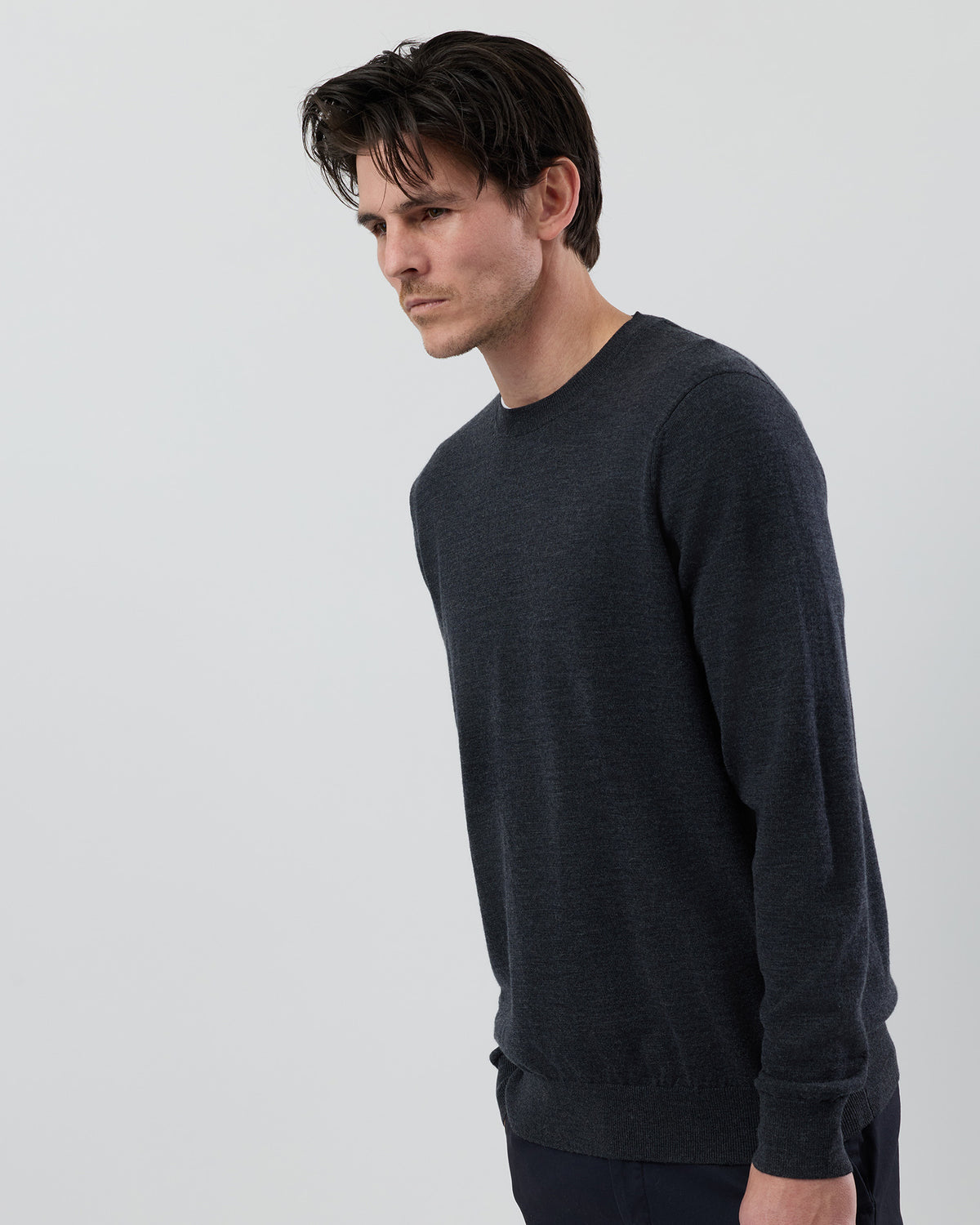 Angled side view of a men's charcoal marl Australian ultrafine merino crew neck sweater highlighting the tailored fit and marl knit texture.