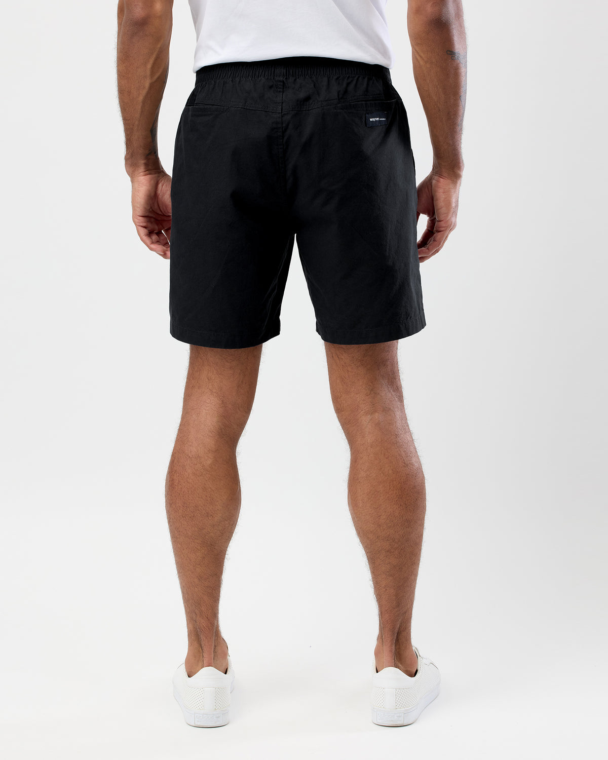 Person wearing black wayver shorts on a white background, rear view