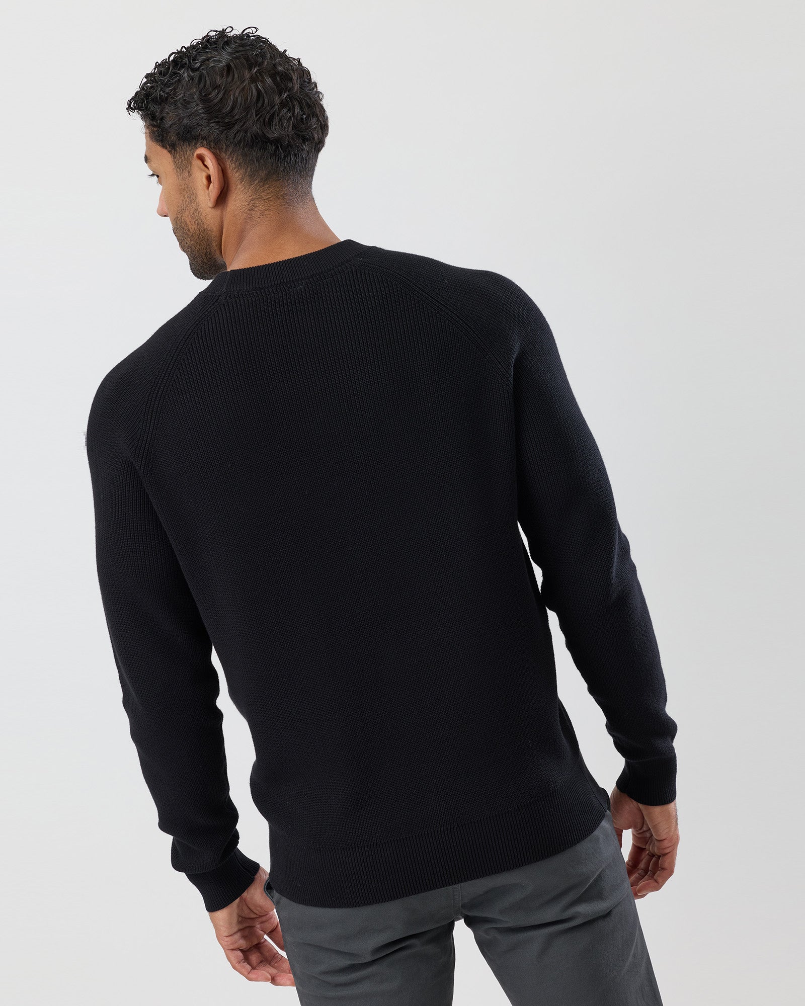 Man wearing a black cotton sweater against a white background