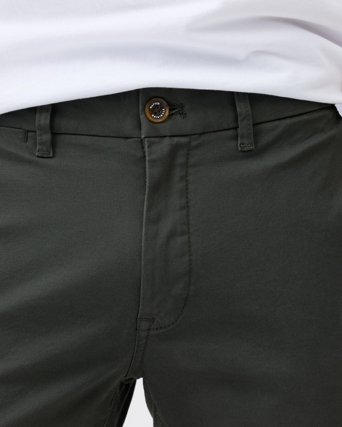 Close-up of dark green pants with a white shirt underneath