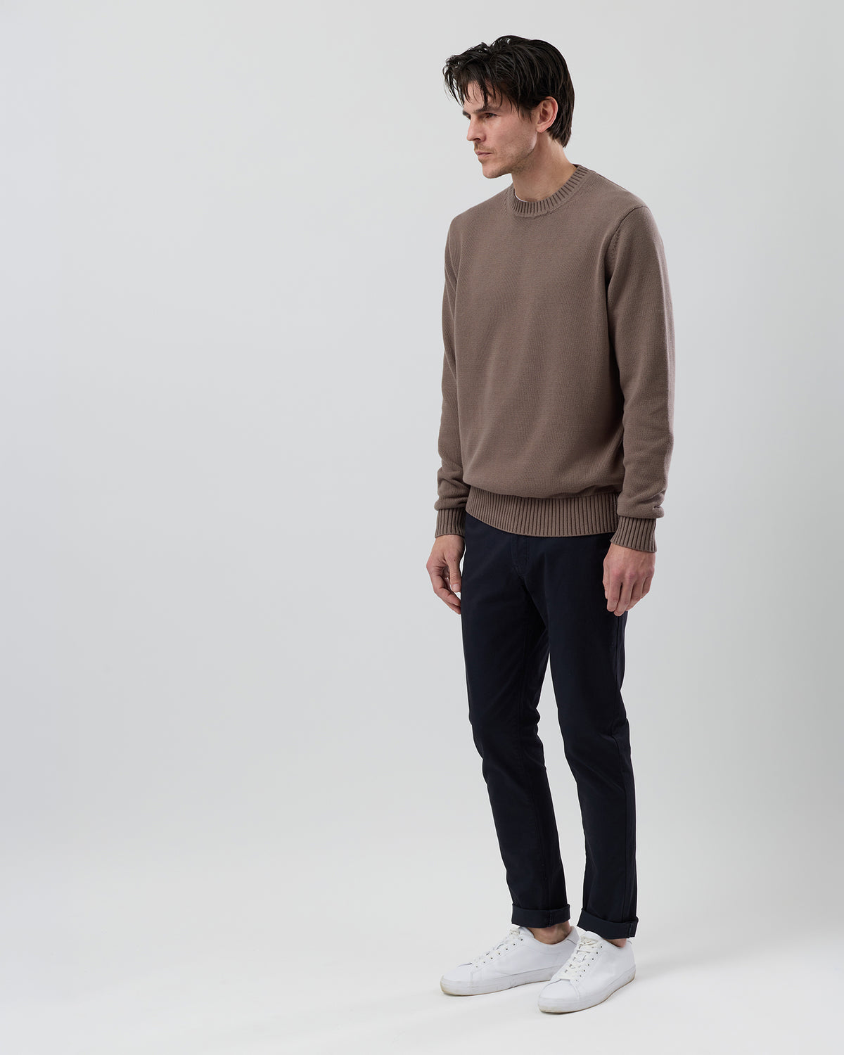 Side profile of a male model wearing the Wayver latte cotton crew neck jumper showing the regular fit and slim sleeve shape.
