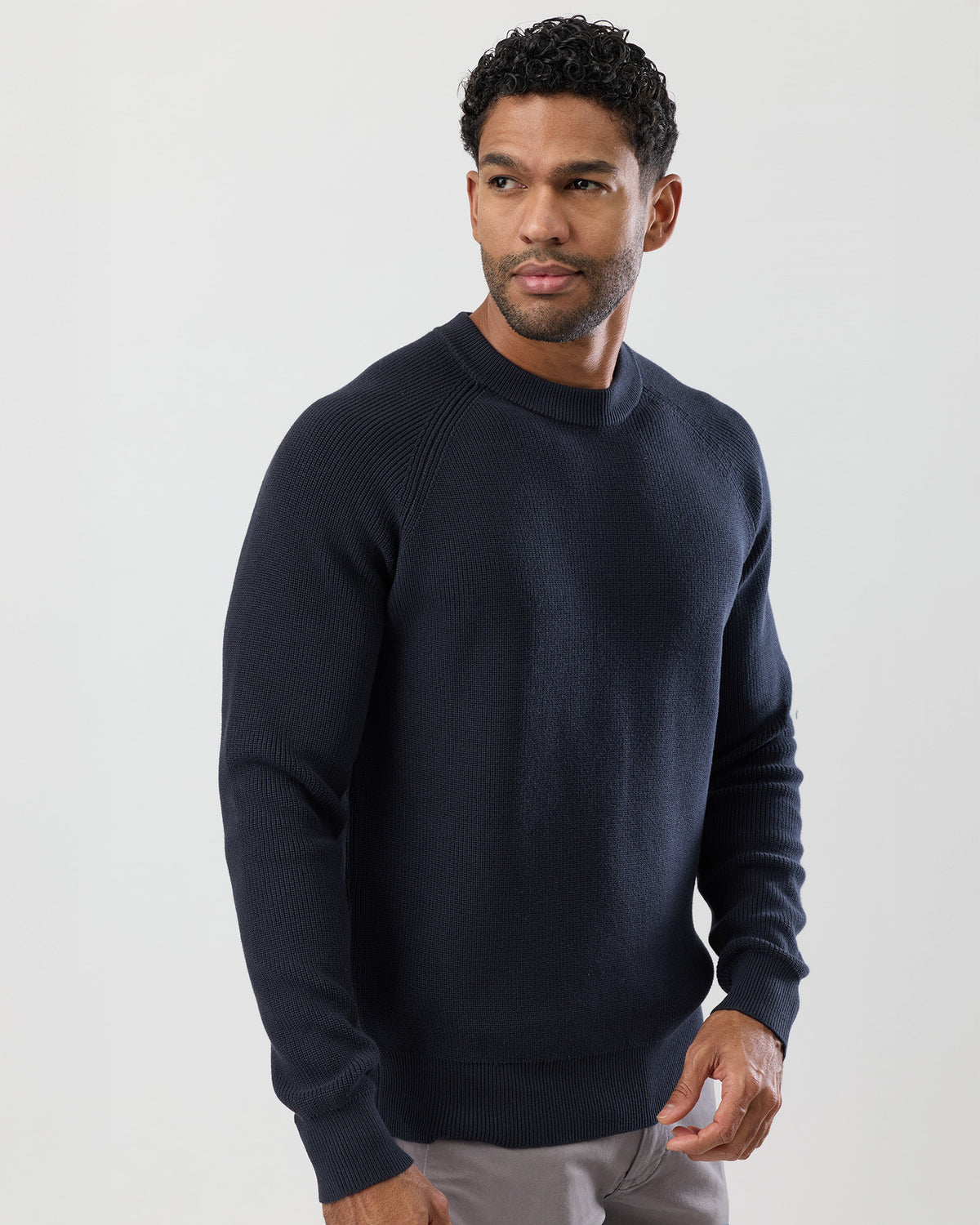 Model wearing a dark navy knitted fishermans crew knit, side view