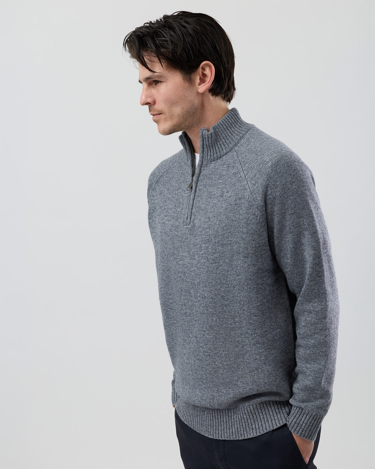Angled side view of a men's grey wool blend quarter zip knit showing the streamlined silhouette and premium 9 gauge jersey knit construction.
