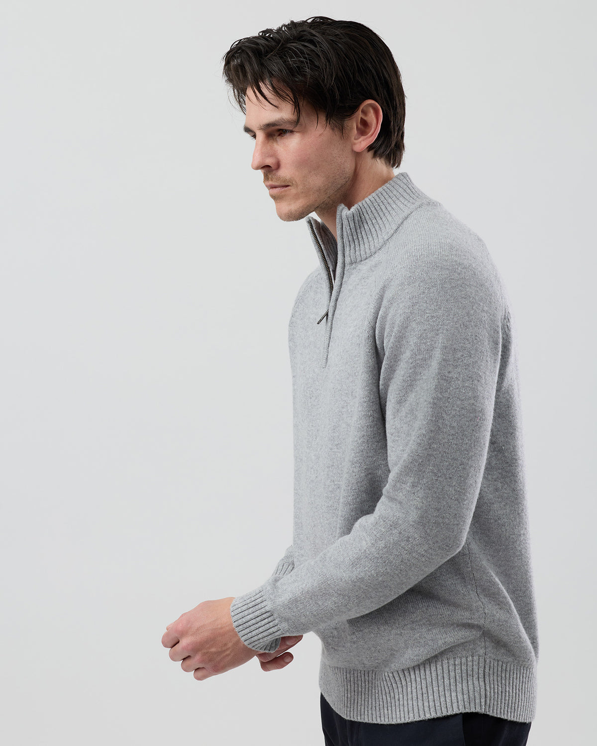 Angled side view of a men's light grey wool blend quarter zip knit showing the refined silhouette and soft jersey knit texture.