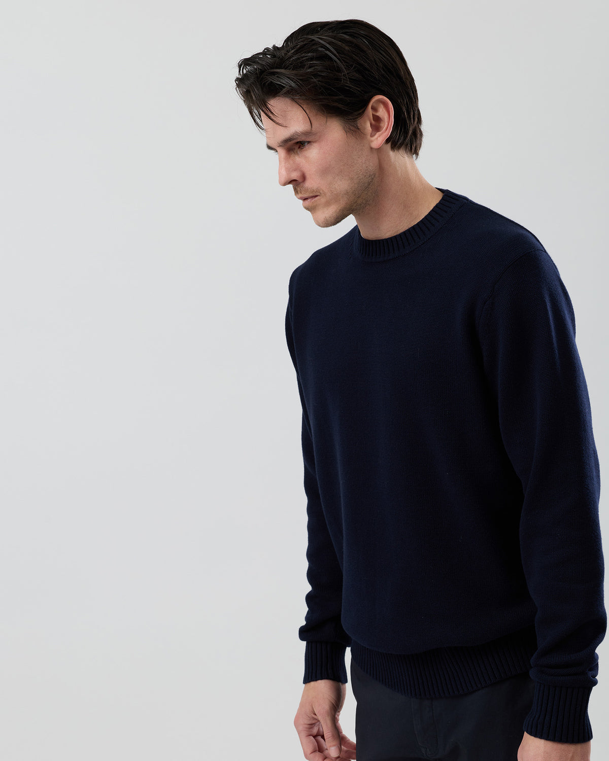 Angled side view of the Wayver navy 100% cotton crew neck knit showing the refined silhouette and premium cotton knit texture.
