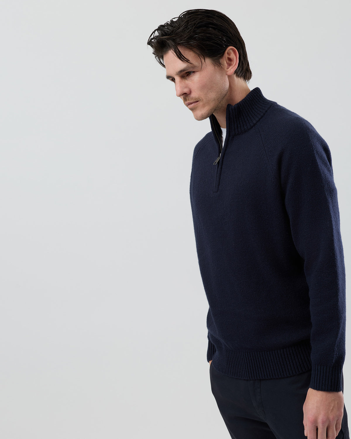 Angled side view of a men's navy wool blend quarter zip knit showing the refined silhouette and premium jersey knit texture.