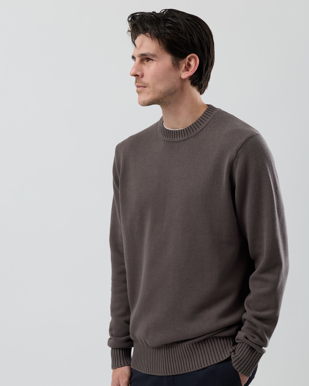 Angled side view of the Wayver slate brown 100% cotton crew neck knit showing the premium cotton texture and refined silhouette.