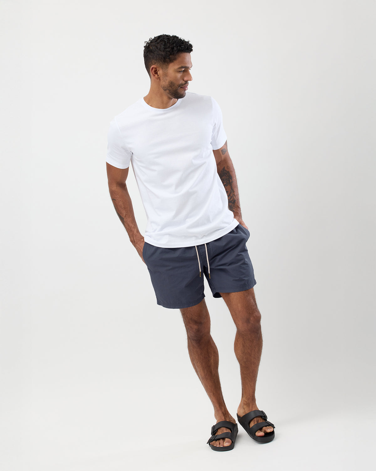 Man wearing a white t-shirt and vintage blue cotton nylon quick drying swim shorts on a white background
