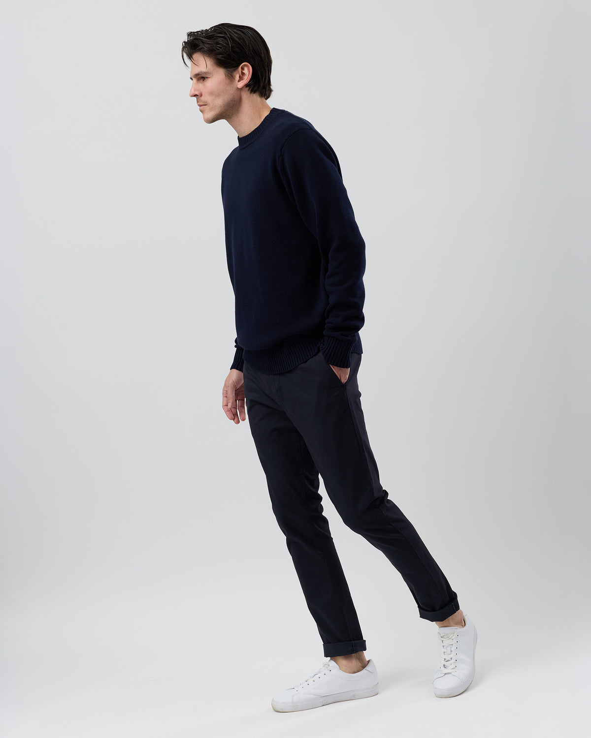 Side profile of a male model wearing the Wayver navy cotton crew neck jumper with navy chinos, showing the comfortable regular fit.