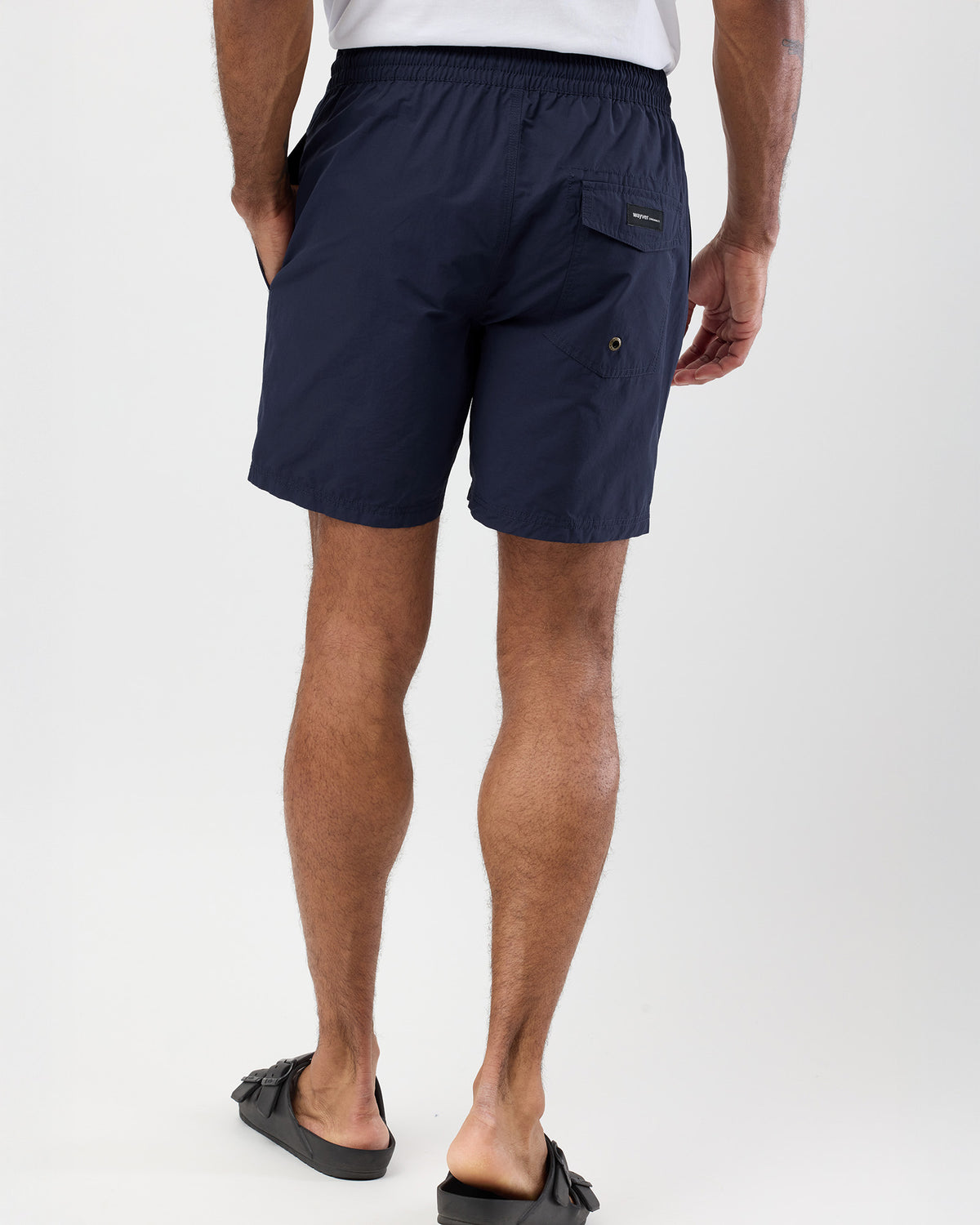 Person wearing navy shorts on a white background, rear shot