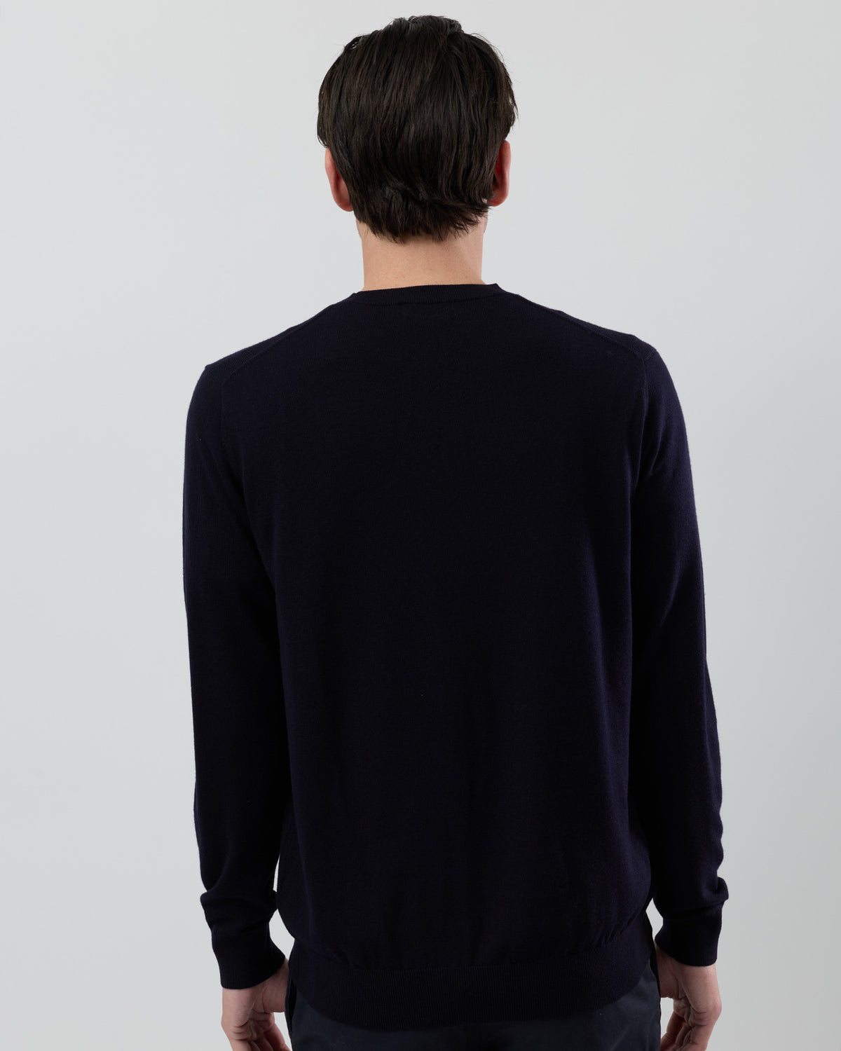Rear view of a men's navy Australian ultrafine merino wool jumper showing the clean back fit and classic crew neck design on a grey background.