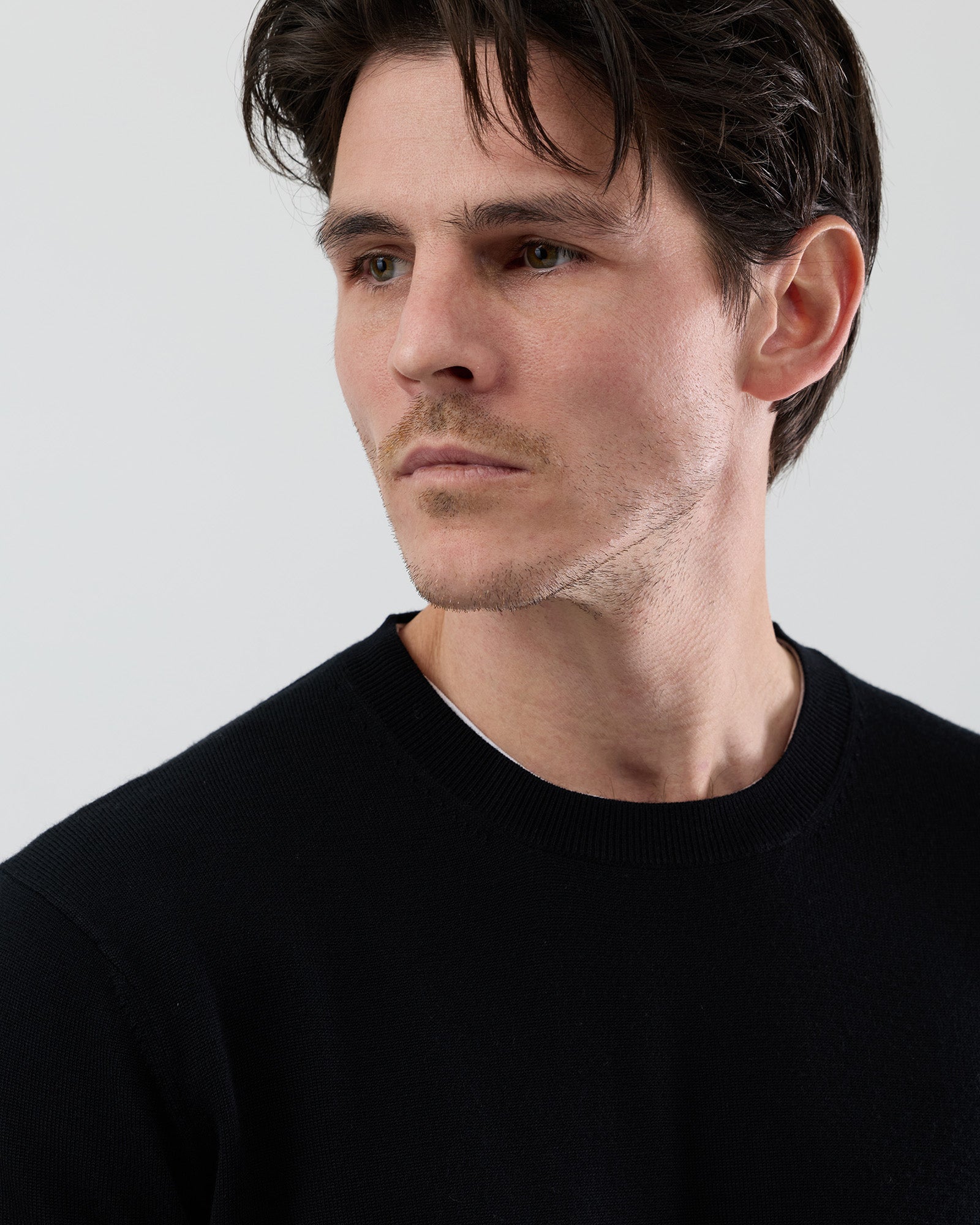 Close-up front image of a men's black Australian ultrafine merino wool crew neck sweater highlighting the fine gauge knit and premium fabric.