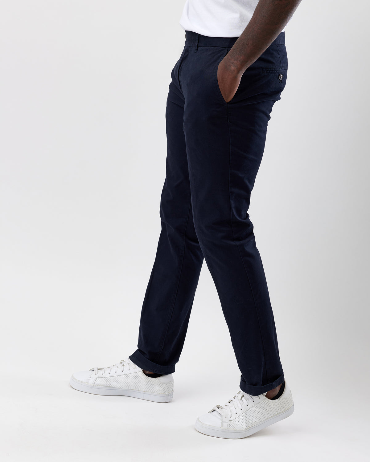 Person wearing Wayver navy chinos and white sneakers on a white background, side view