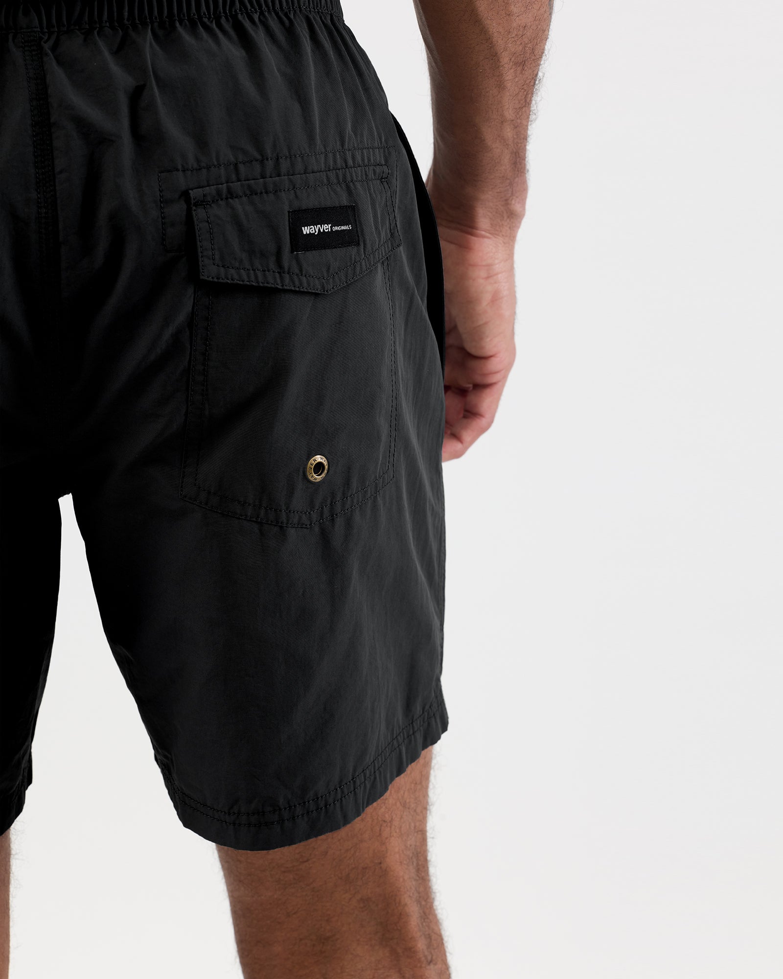 Person wearing black shorts with a white drawstring on a light gray background, close up shot