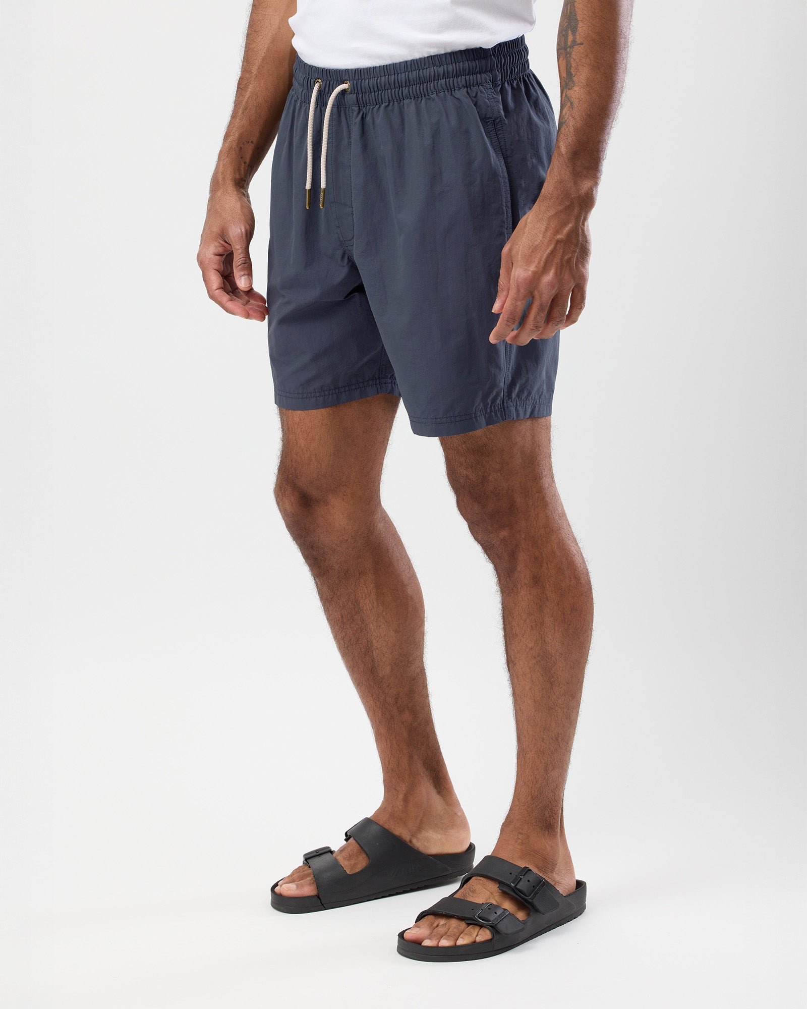 Person wearing vintage blue summer board shorts and black sandals on a white background