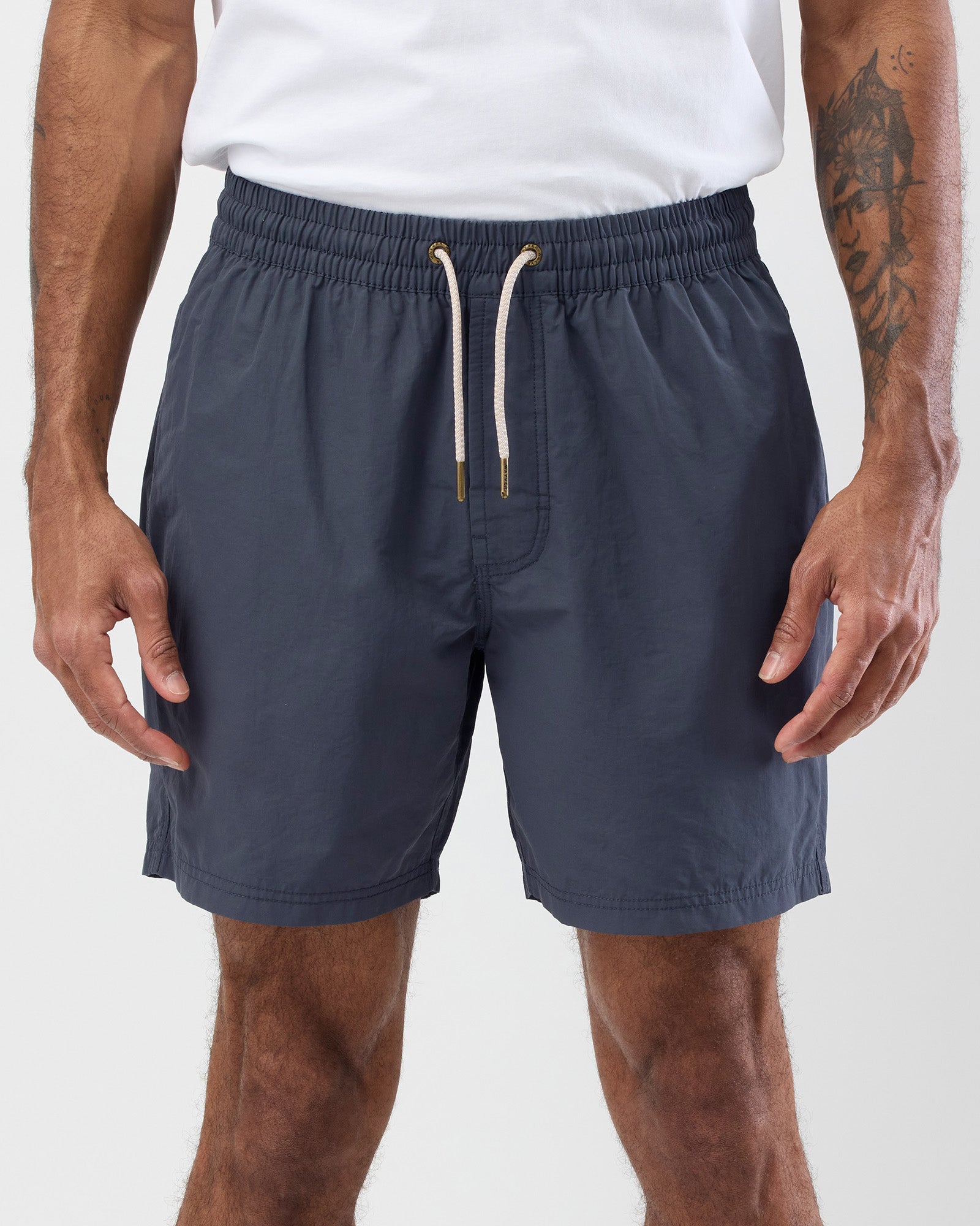 Person wearing vintage blue shorts with drawstring and a white background, close up shot