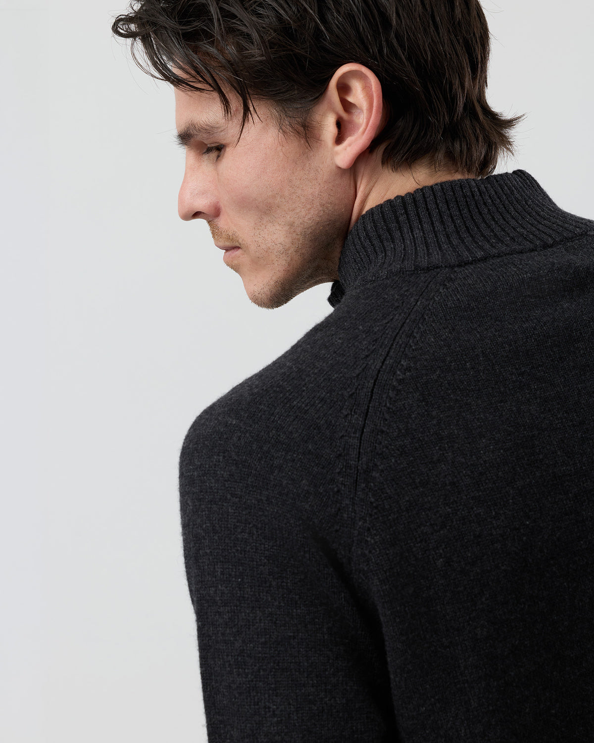 Close-up rear shoulder detail of the Wayver charcoal wool blend knit showing the structured shoulder construction, stand collar shape and 9 gauge jersey knit texture.