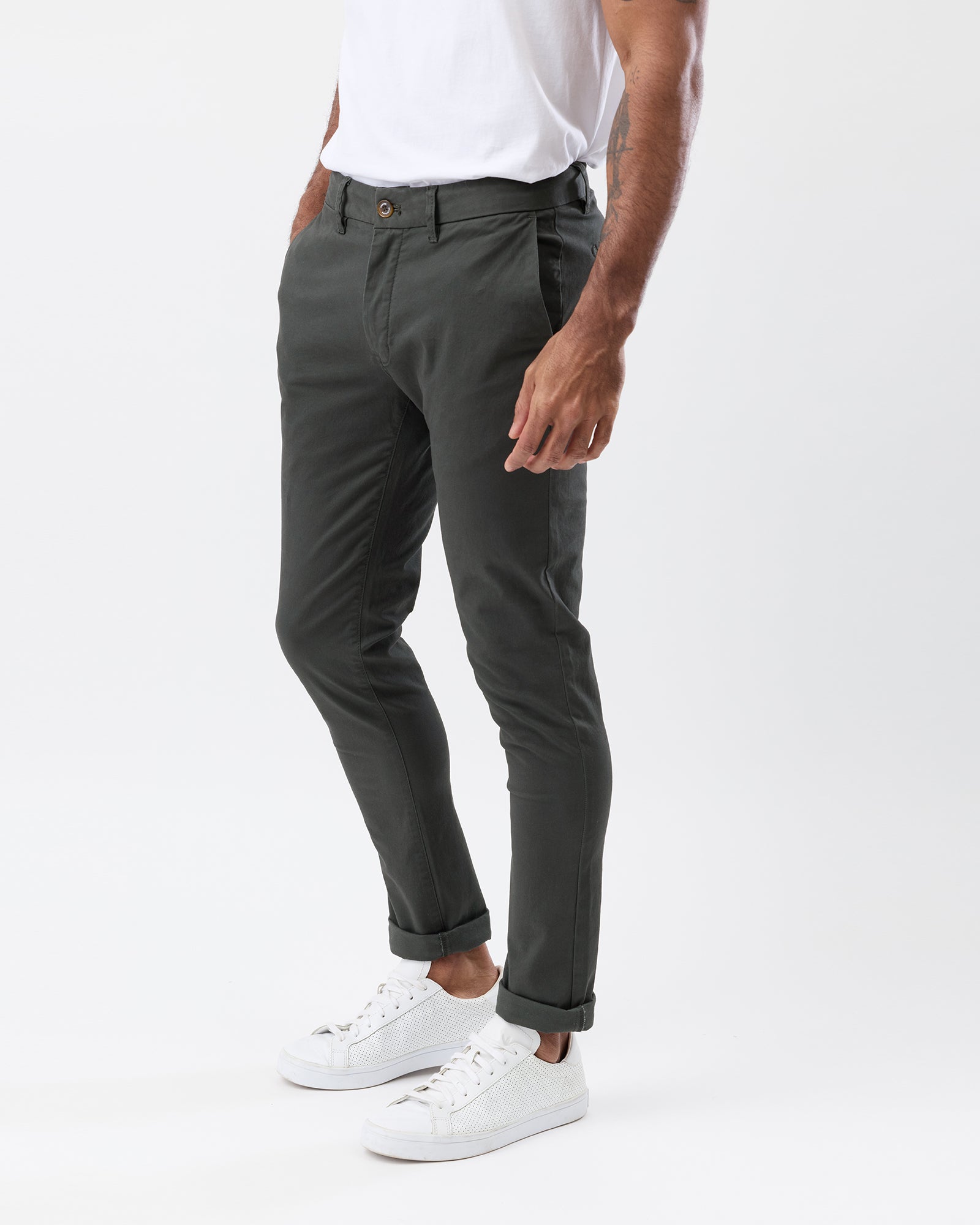 Person wearing dark green pants and white sneakers on a white background