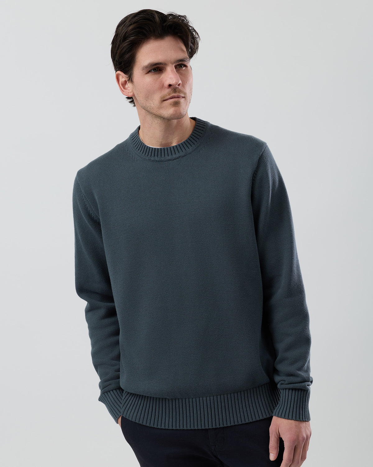 Male model wearing the Wayver Essential Cotton Crew Neck Knit in ironstone, front view showing the regular fit, slim sleeves and classic crew neck design.