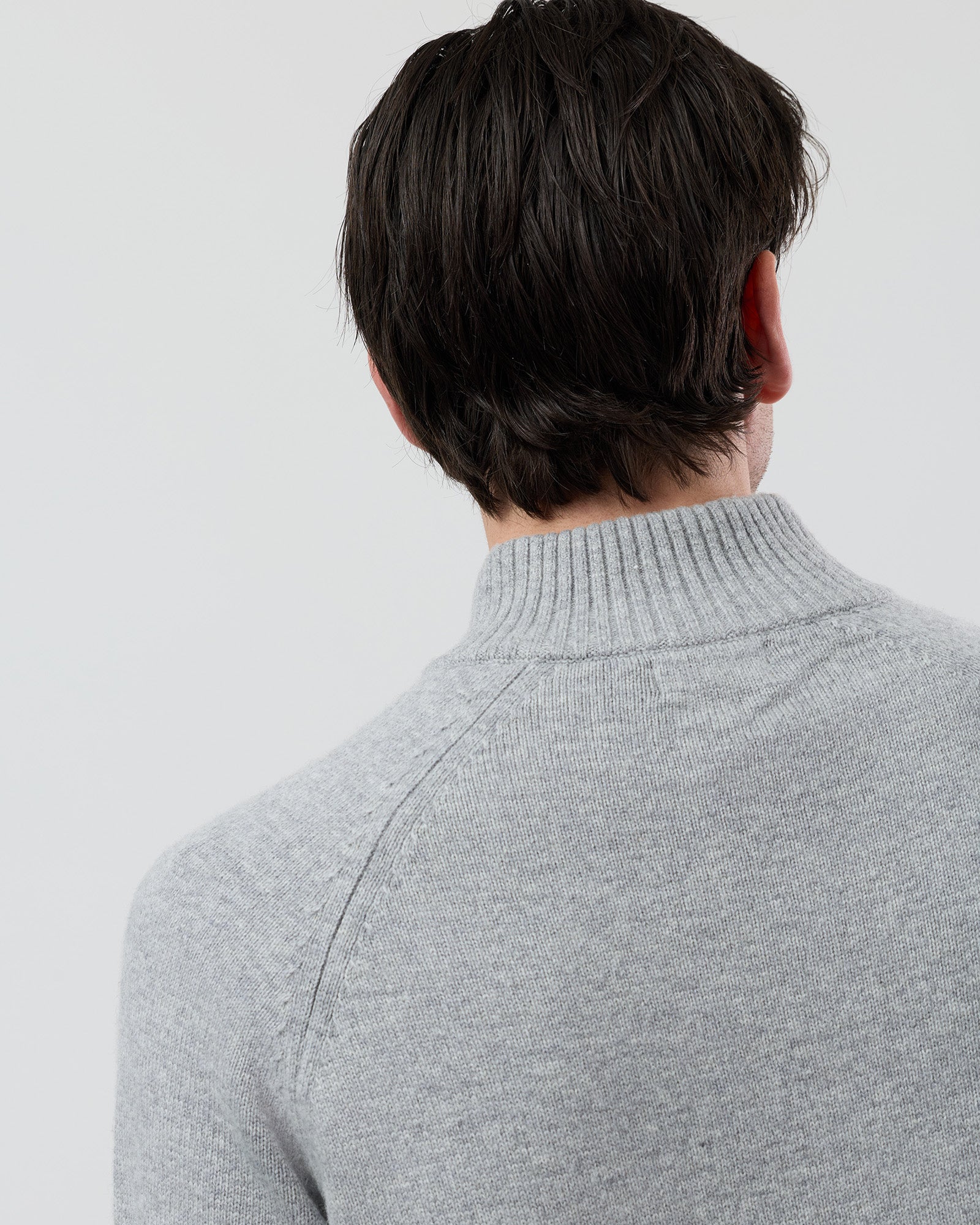 Close-up rear shoulder detail of the Wayver light grey wool blend knit showing the structured shoulder design, stand collar and premium 9 gauge jersey knit texture.