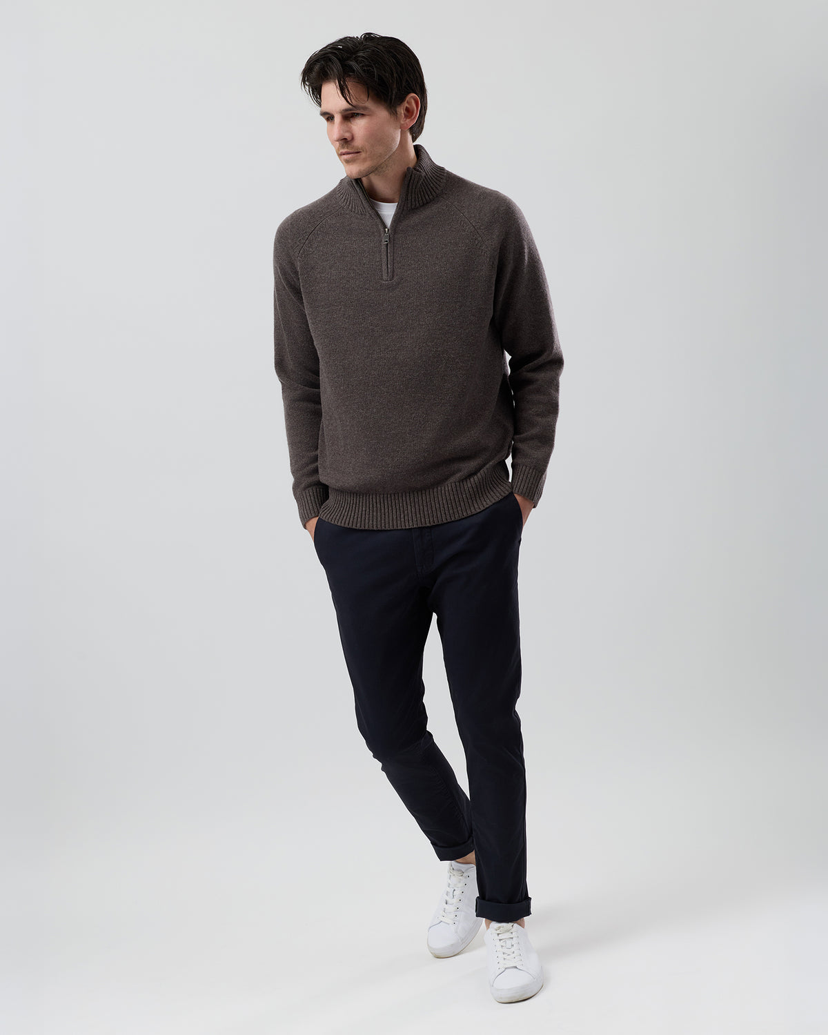 Full-length front view of a male model wearing the Wayver brown marl wool blend half zip knit styled with navy chinos on a grey background.