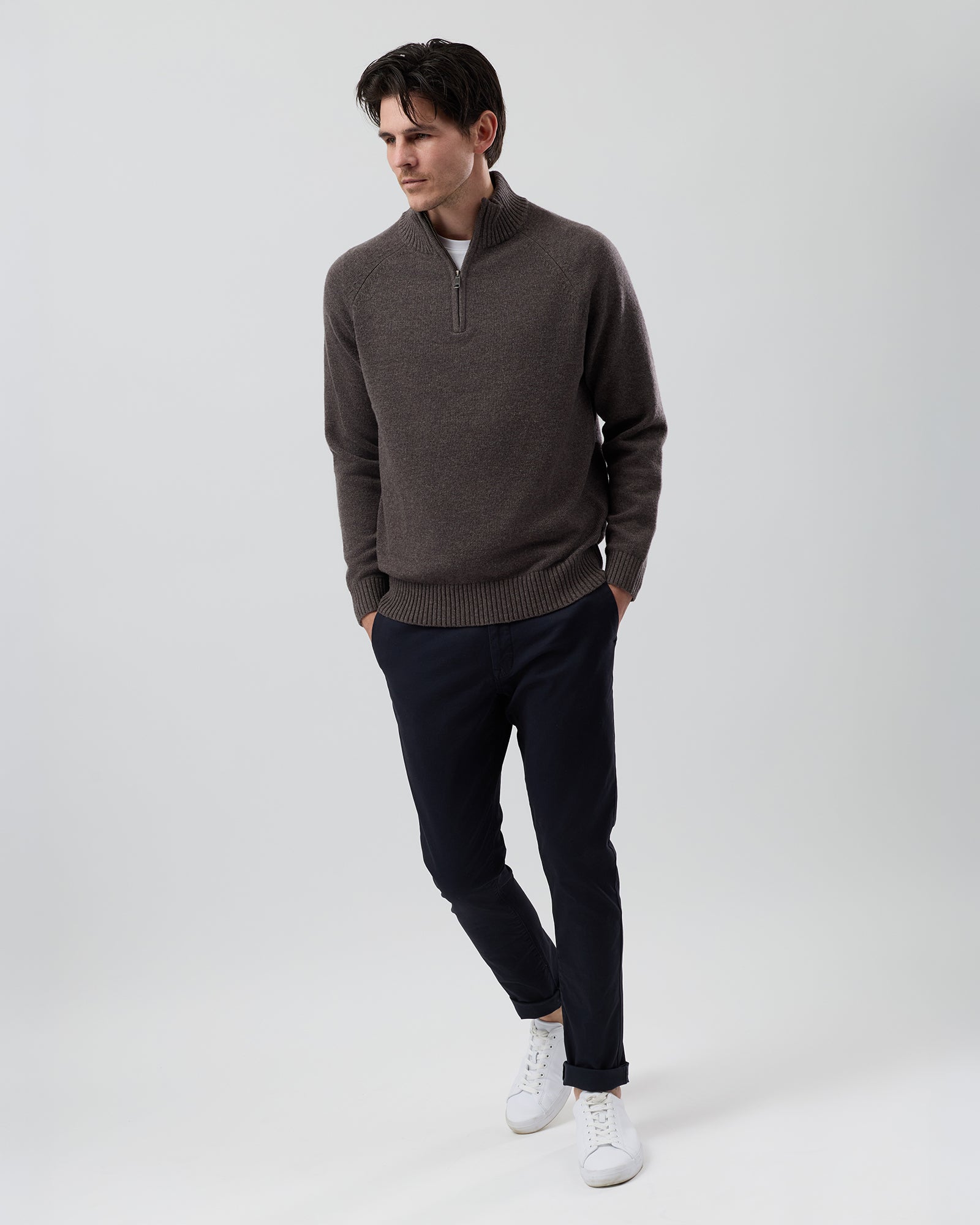 Full-length front view of a male model wearing the Wayver brown marl wool blend half zip knit styled with navy chinos on a grey background.