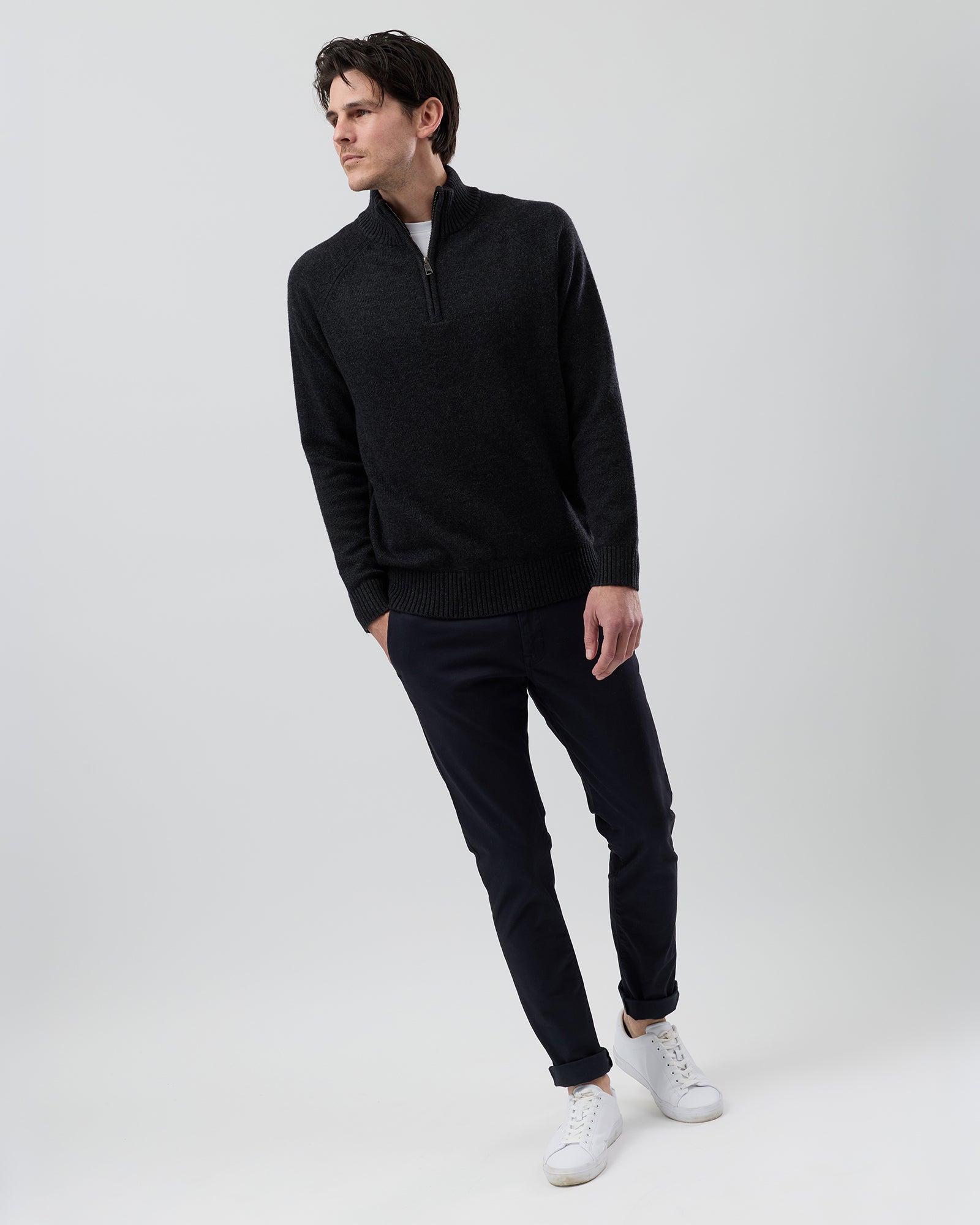 Full-length front view of a male model wearing the Wayver charcoal wool blend half zip knit styled with navy chinos on a grey background.