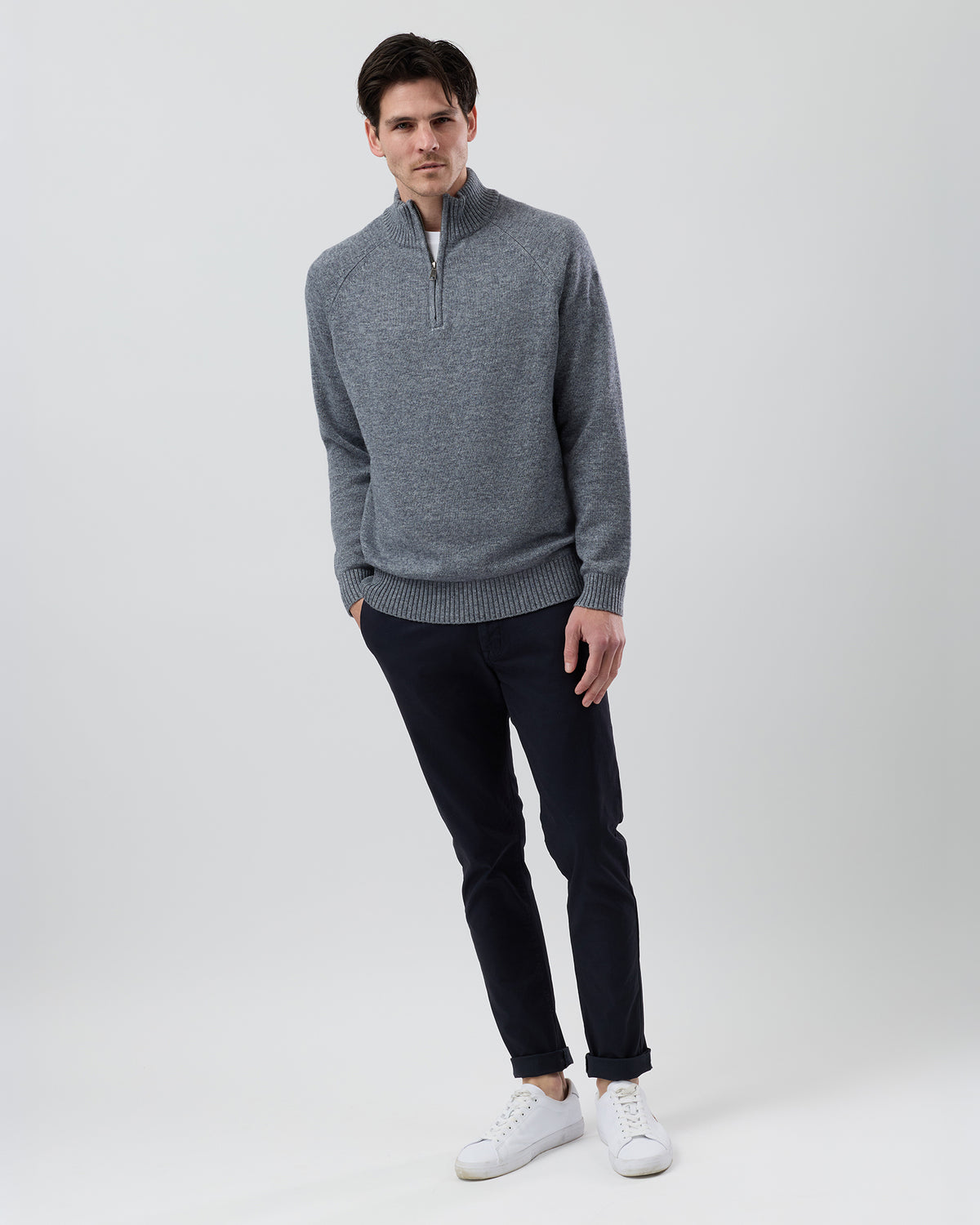 Full-length front view of a male model wearing the Wayver grey wool blend half zip knit styled with navy chinos on a grey background.