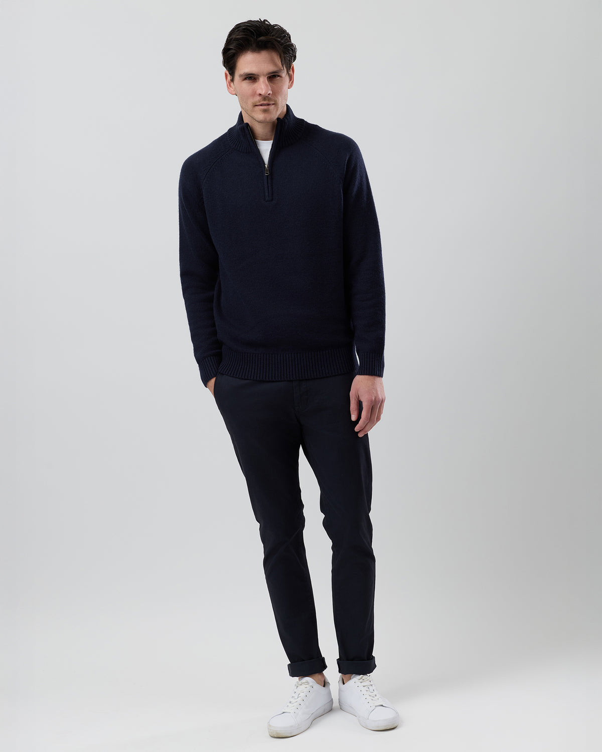 Full-length front view of a male model wearing the Wayver navy wool blend half zip knit styled with navy chinos on a grey background.