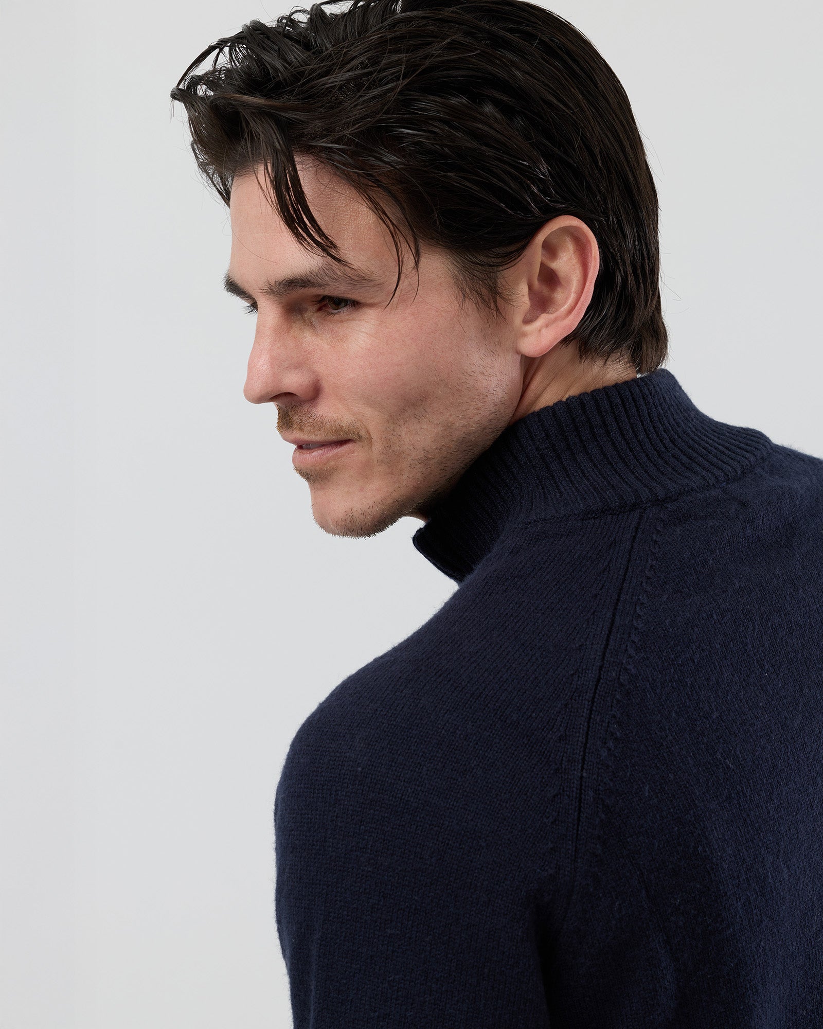 Close-up rear shoulder detail of the Wayver navy wool blend knit showing the structured shoulder construction, stand collar and fine 9 gauge jersey knit texture.