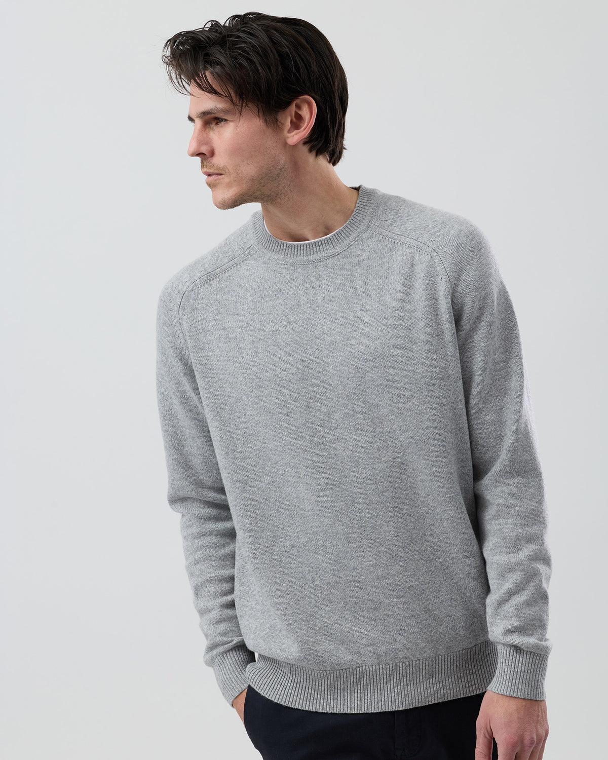 Male model wearing the Wayver Originals light grey wool blend crew neck knit jumper  on a grey background, front cropped view highlighting the fit through the chest and sleeves.