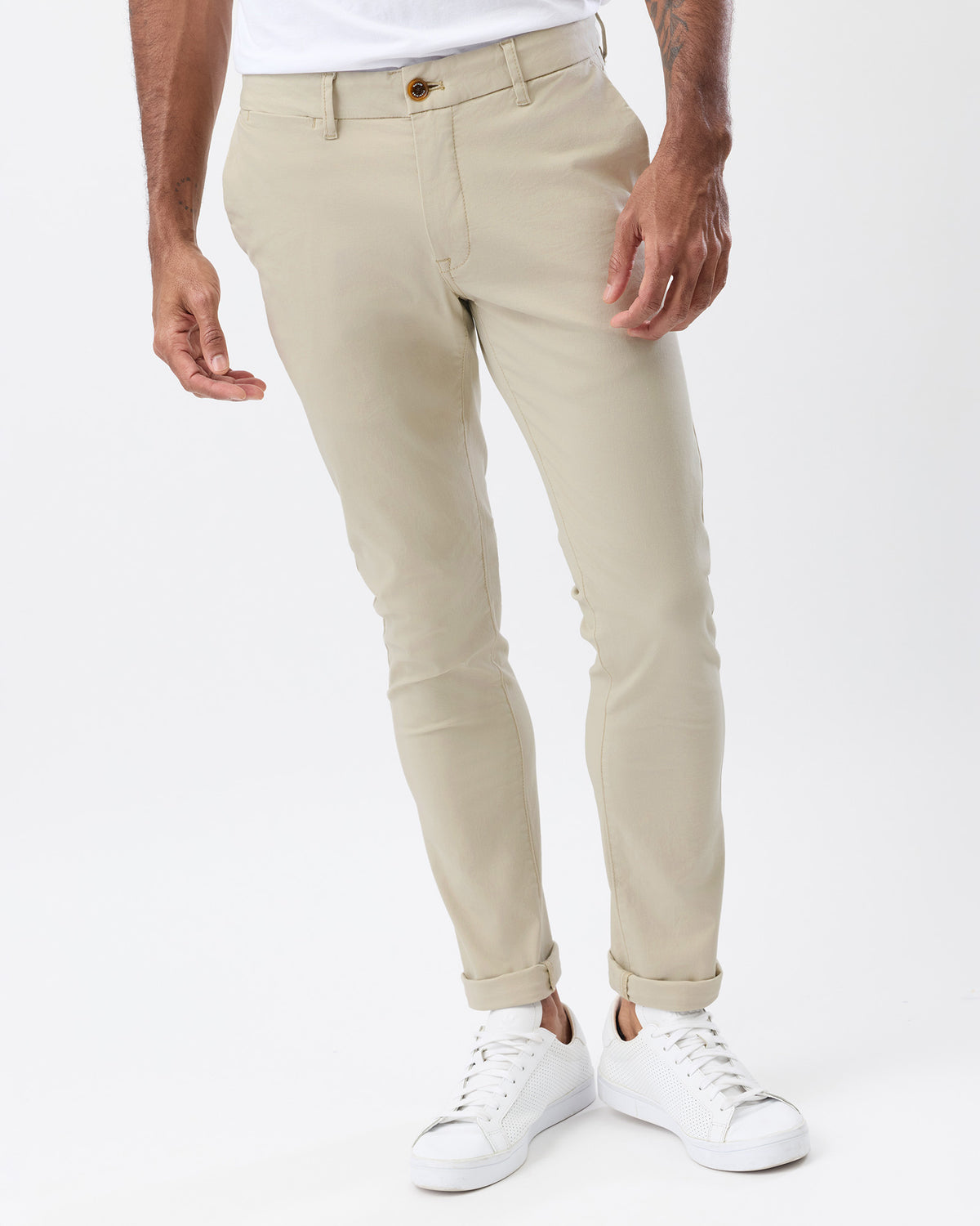 Front view of men's beige tapered chinos highlighting the slim fit through the thighs, front pockets and rolled cuffs.